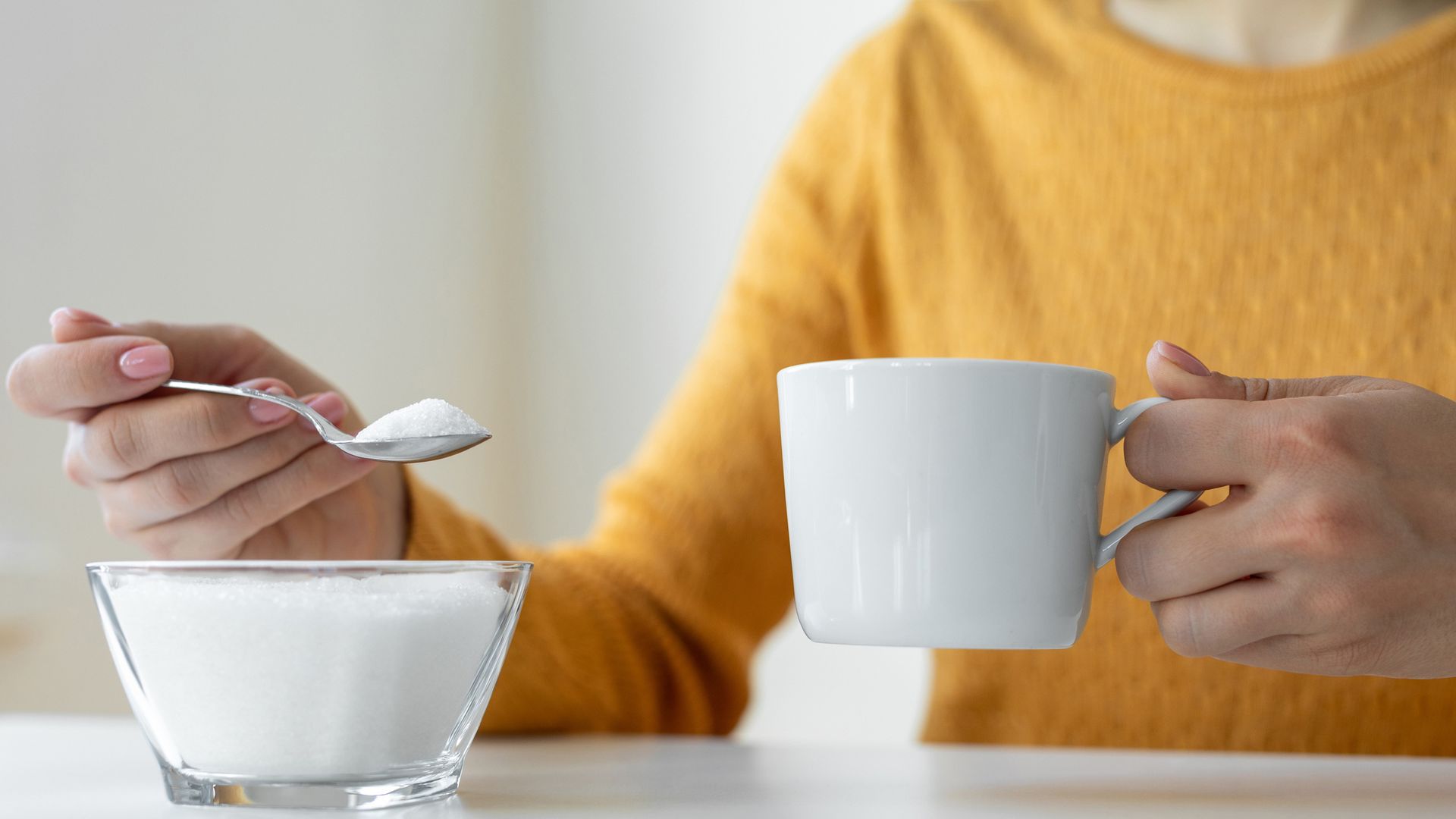 Woman adding sugar to hot drink