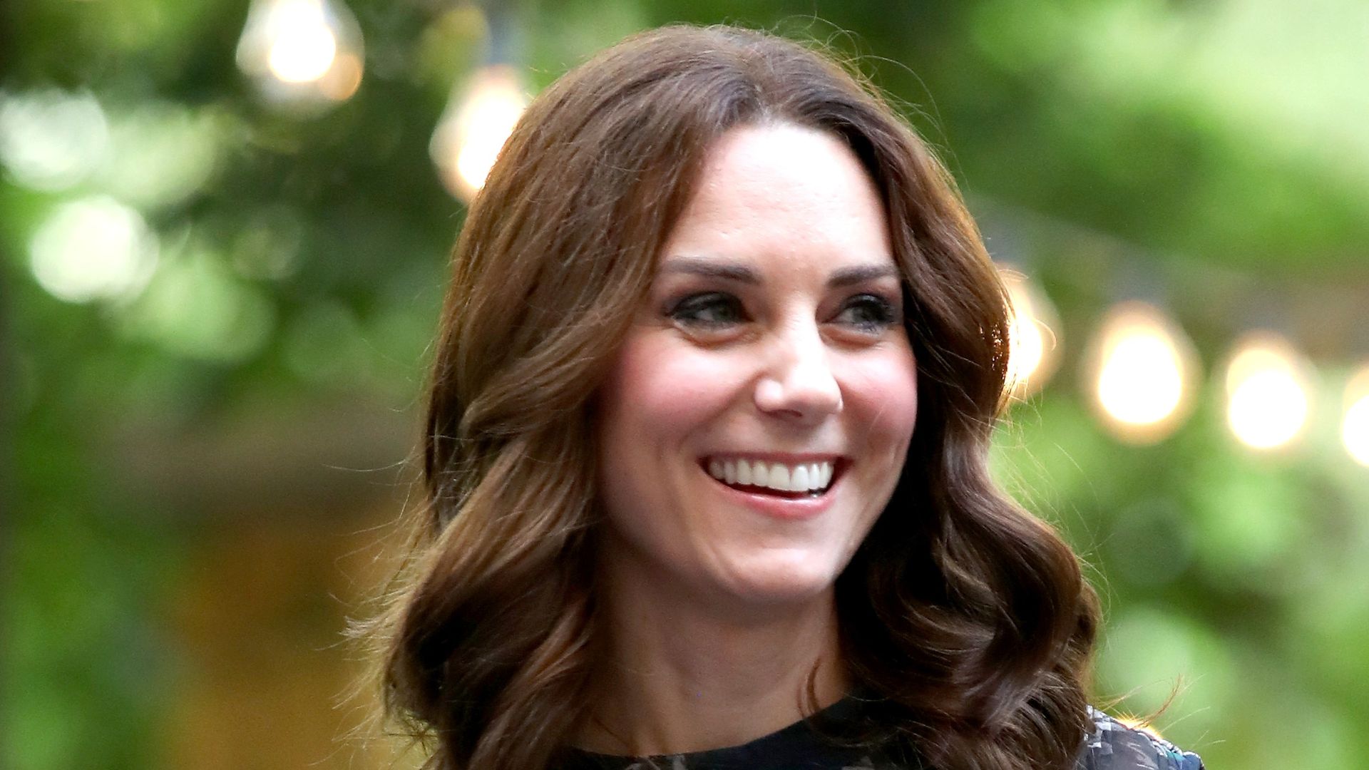 Princess Kate smiling in printed green and blue dress with bob haircut