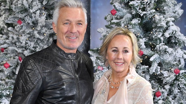 Shirlie Kemp in white with Martin Kemp in leather in front of Christmas trees