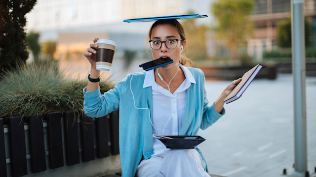 Young businesswoman balancing all of her daily items while sitting outside her office building