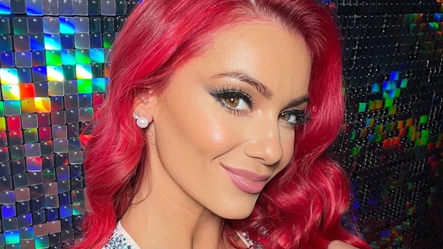 Strictly star Dianne Buswell with red curly hair posing against reflective background