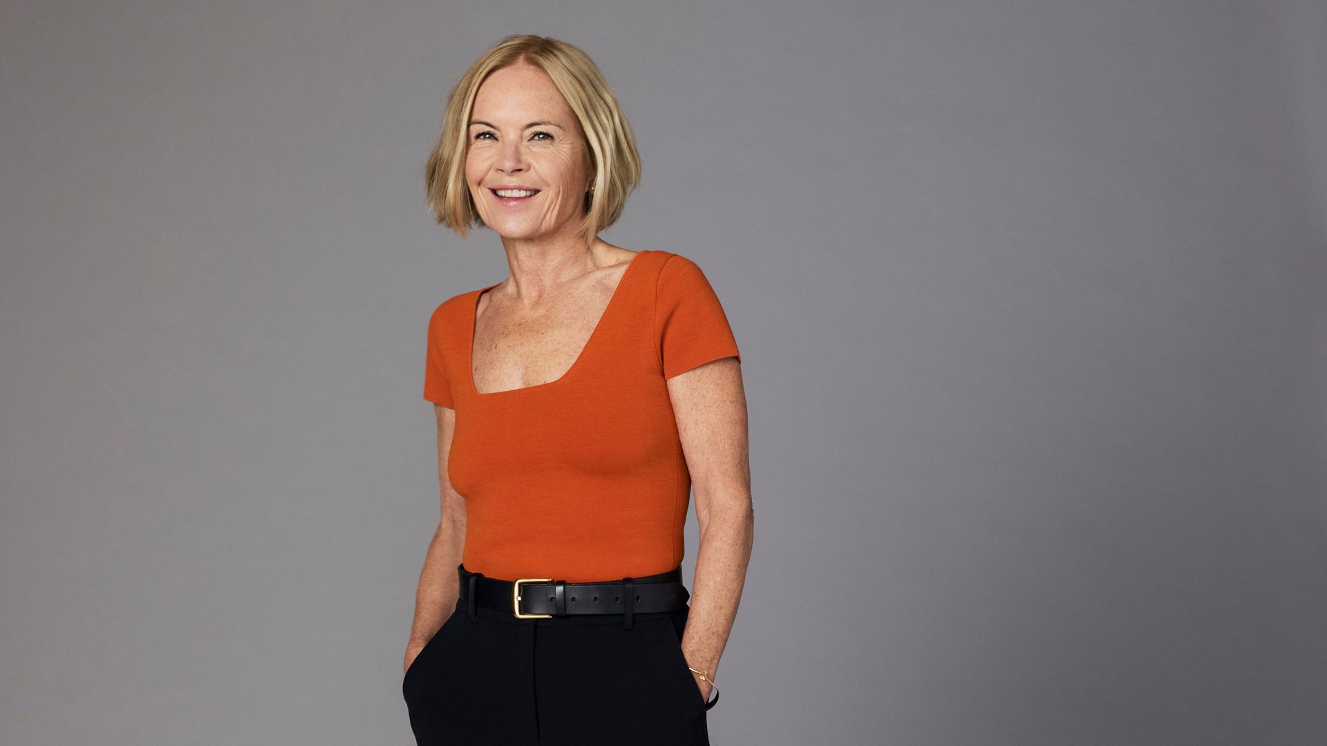 woman in black trousers and a red top with her hands in her pockets 