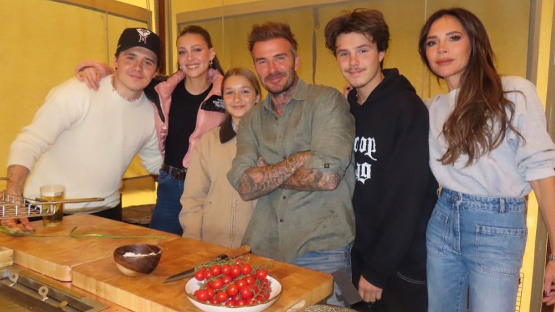 Brooklyn Beckham standing with Nicola Peltz, Harper Beckham, David Beckham, Cruz Beckham and Victoria Beckham in front of food