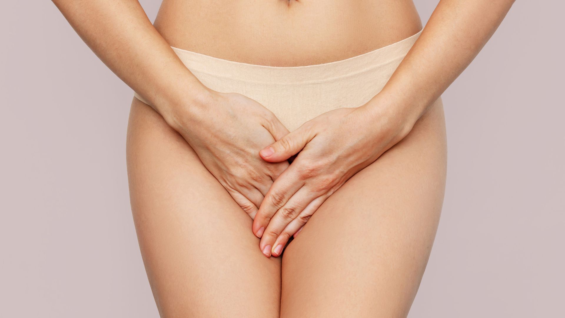 woman in beige underwear covering crotch area