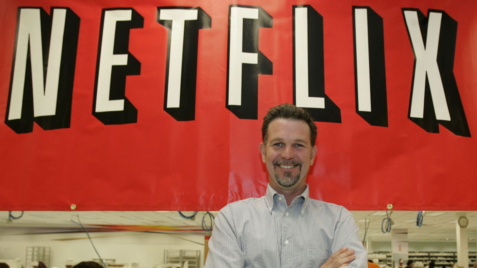 Reed Hastings poses in front of the Netflix sign. 