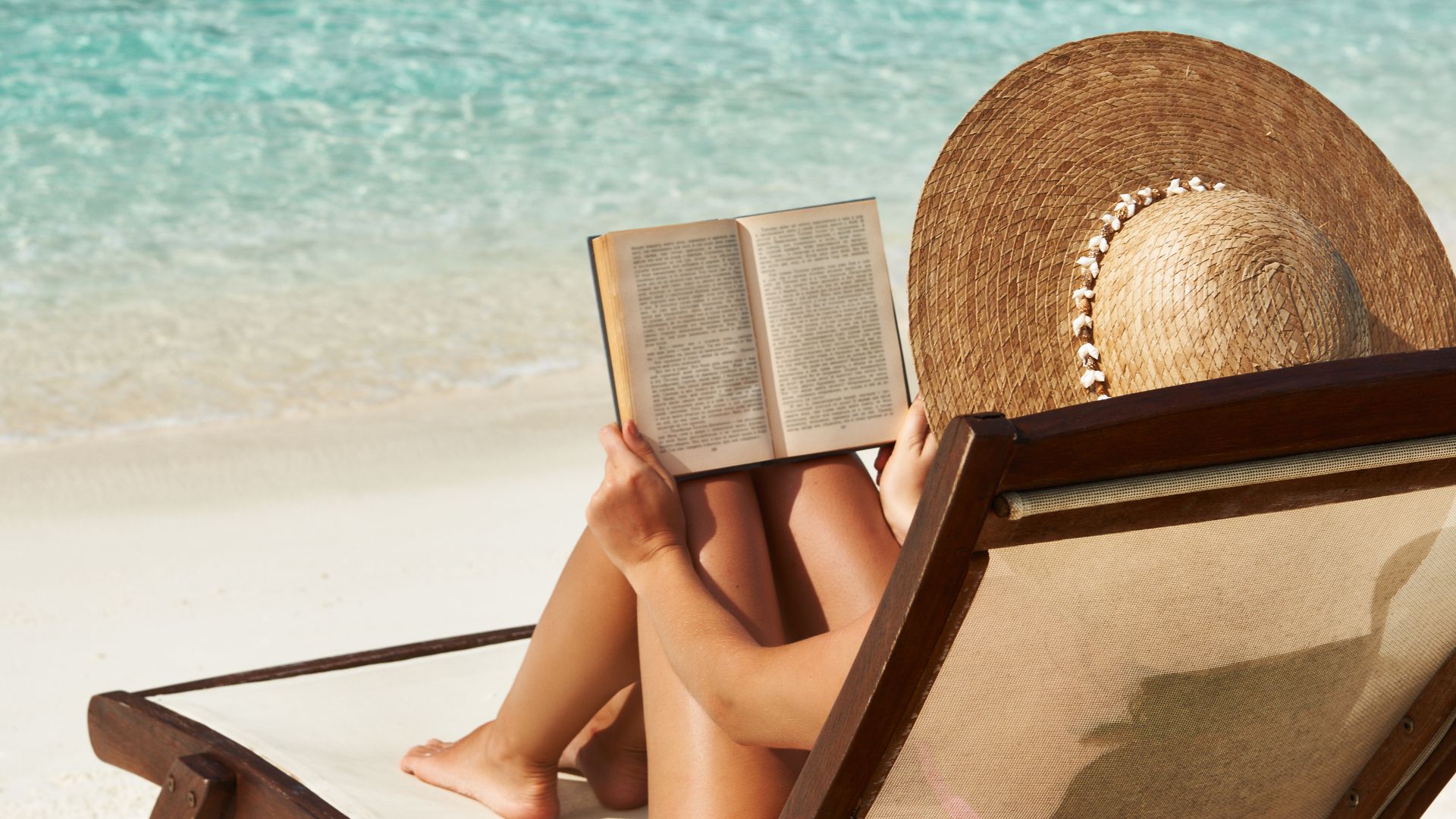 woman reading book sun lounger on the beach