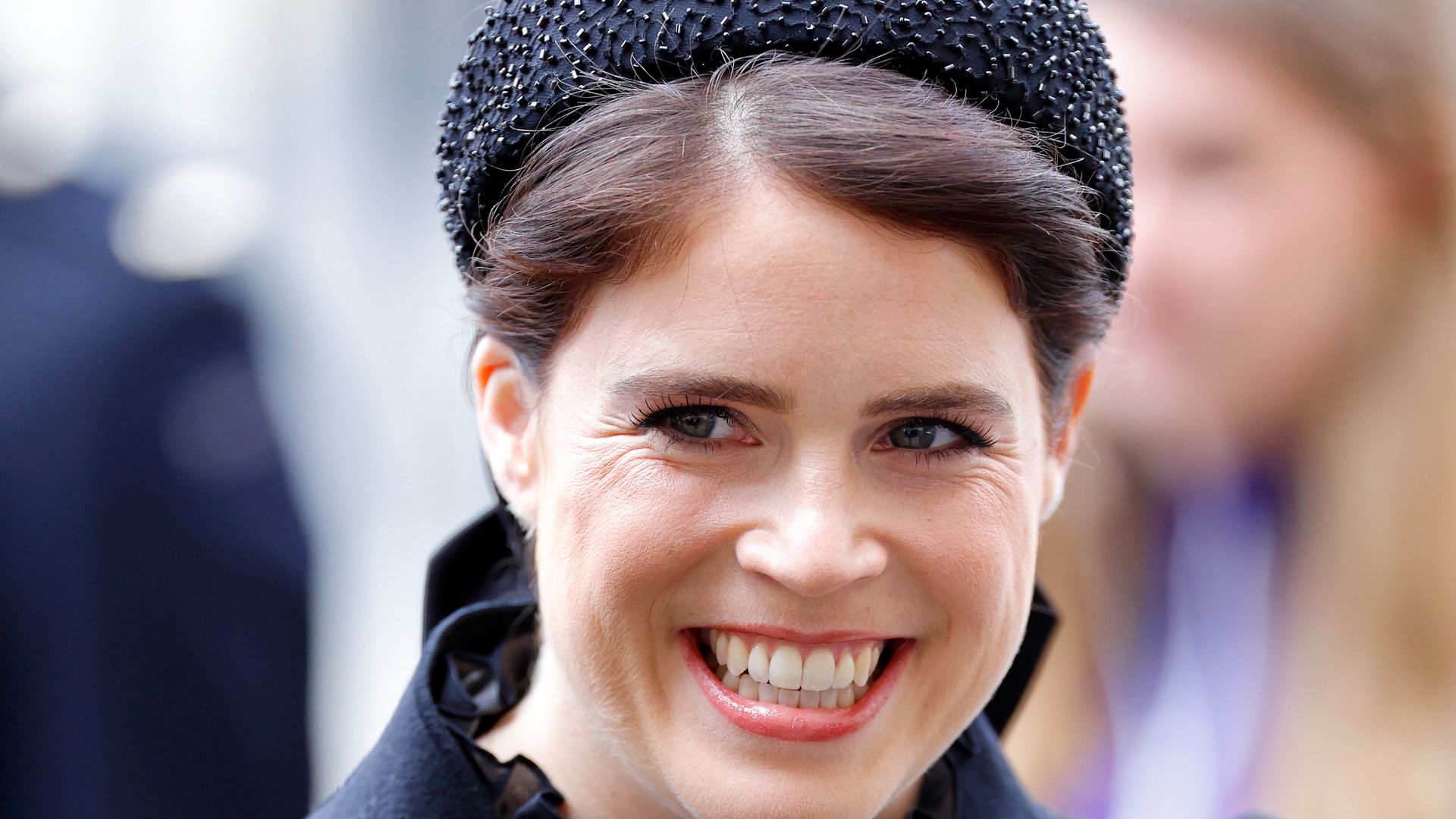 Princess Eugenie grinning wearing black headband