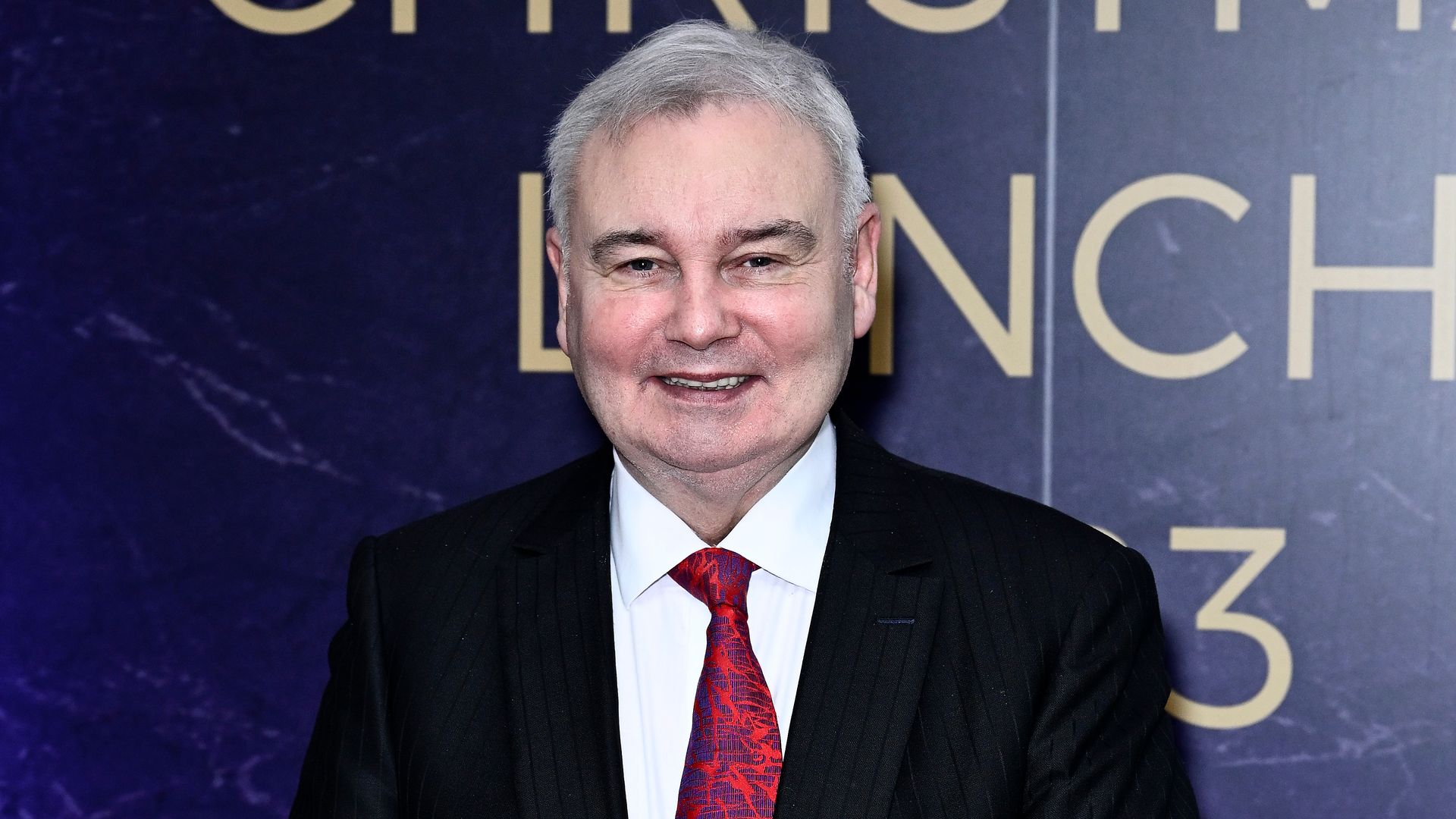 Eamonn Holmes in a black suit with a black cane
