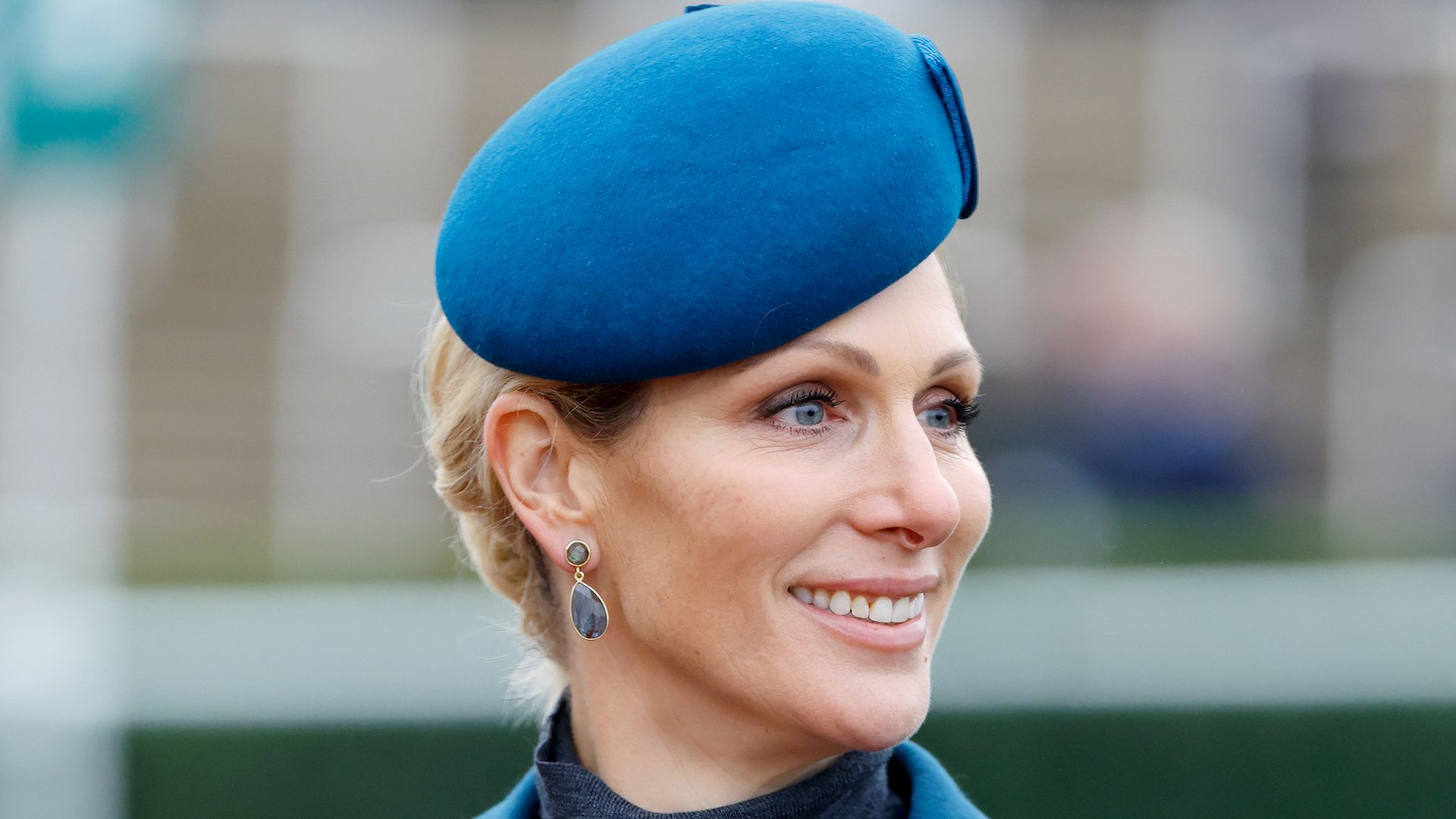 Zara Tindall looking to right in petrol blue hat and coat
