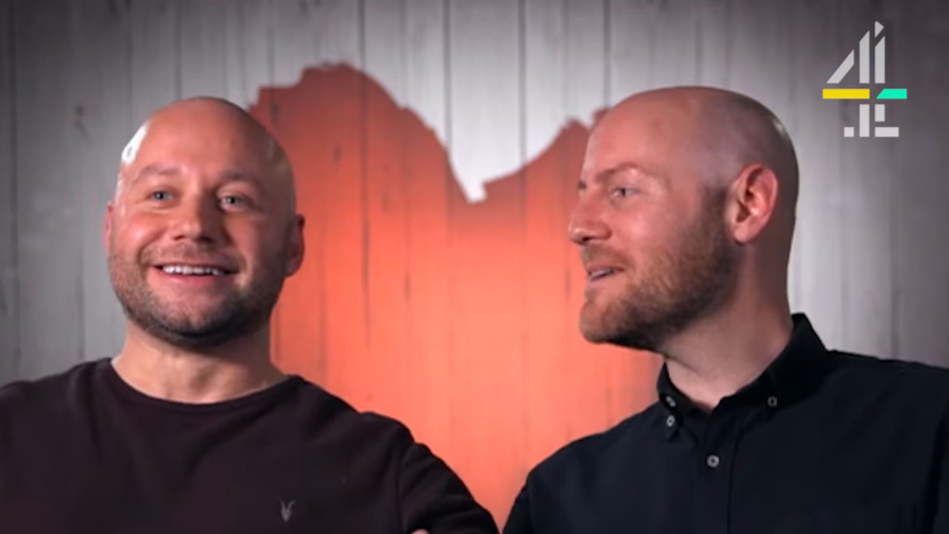 A homosexual couple sitting in front of a heart