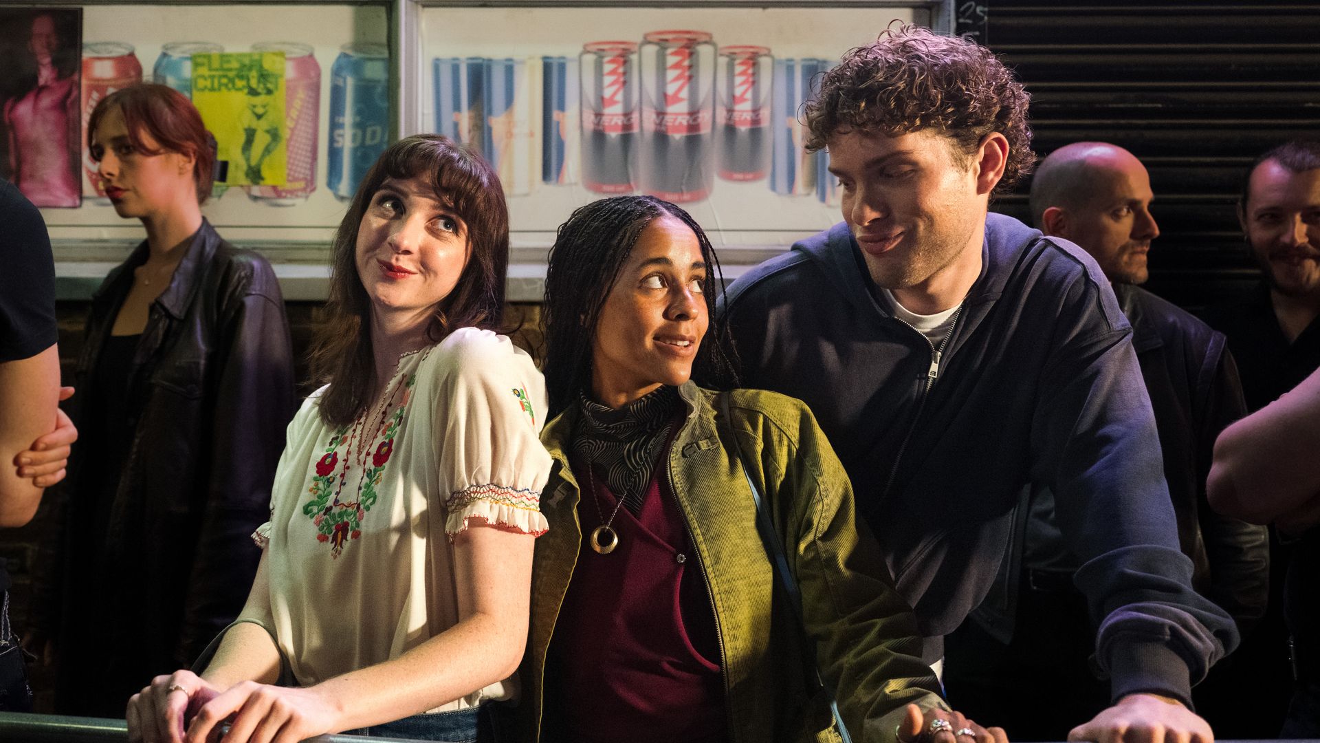 three young people standing in queue outdoors