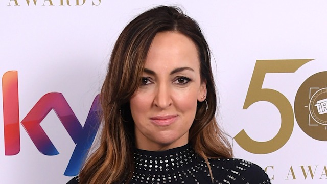 Sally Nugent stands in front of Sky step-and-repeat wearing a black dress at TRIC Awards
