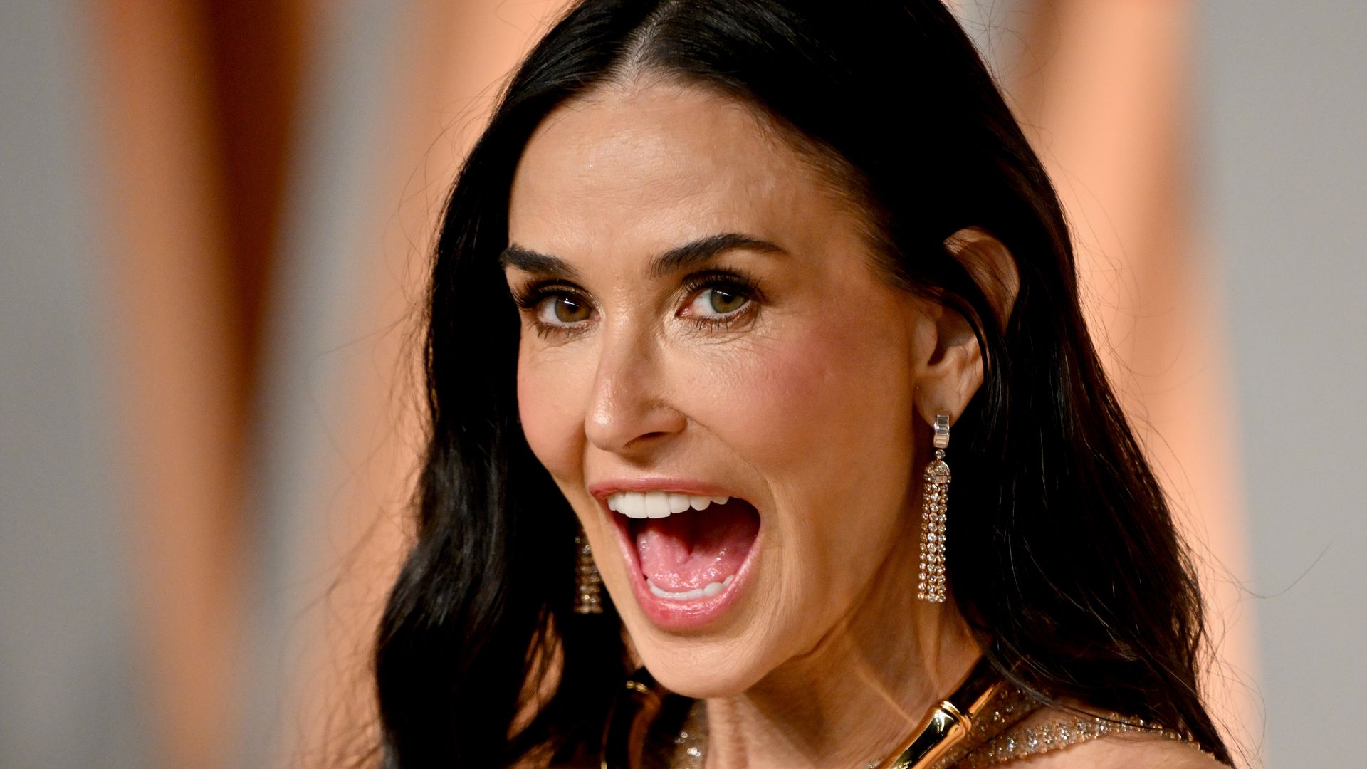 demi moore with long dark hair wearing gold halter dress 