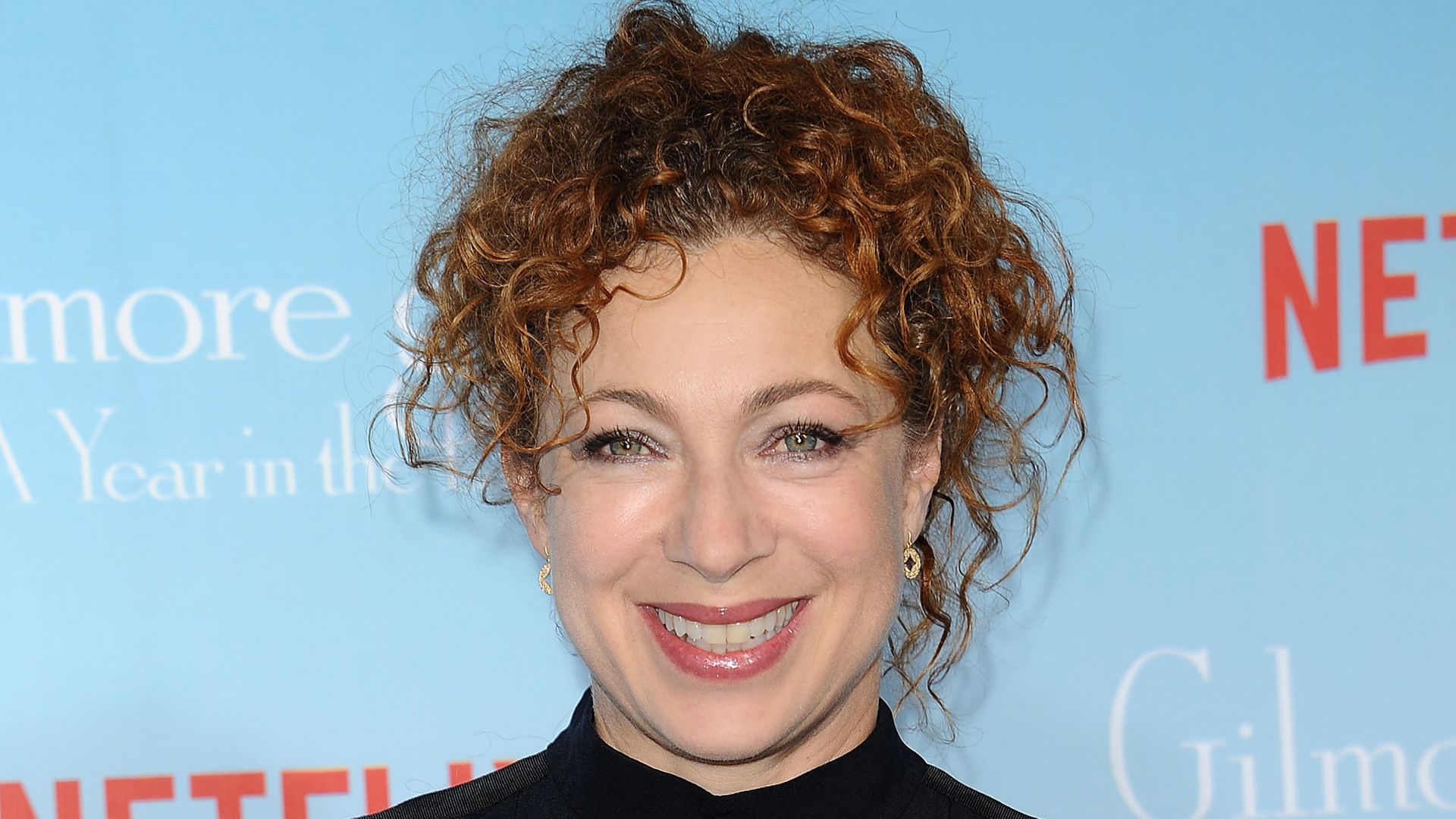 Alex Kingston smiling in a black dress