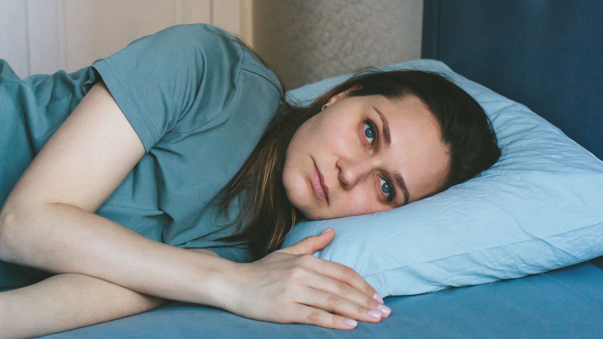 A beautiful woman is lying in bed. Asleep, trying to sleep. The concept of insomnia, sleep problems, loneliness, home comfort, wellness, harmony, inner freedom, feminism.