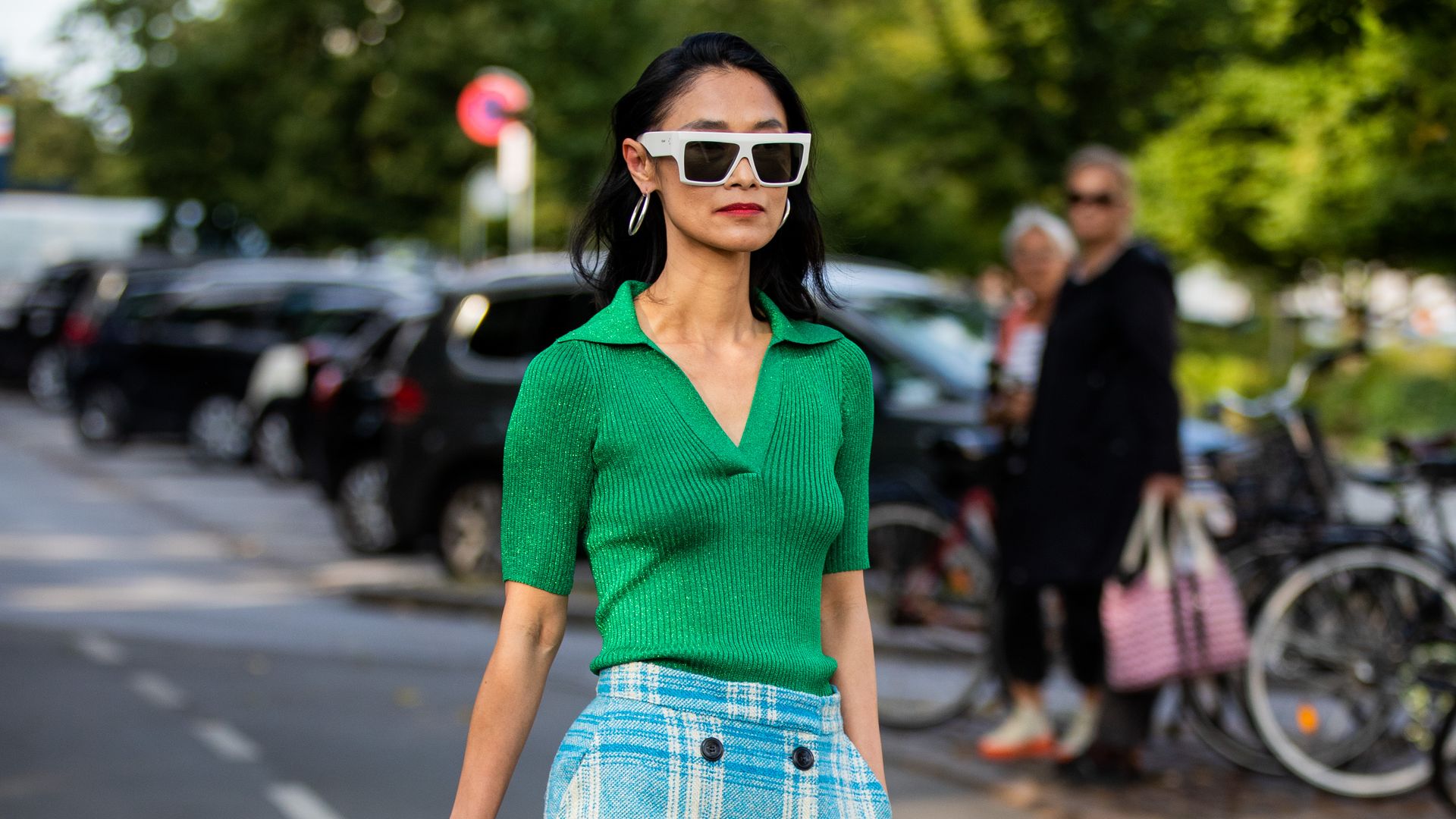 A Fashion Week guest a plaid skirt with a vibrant open collar top 