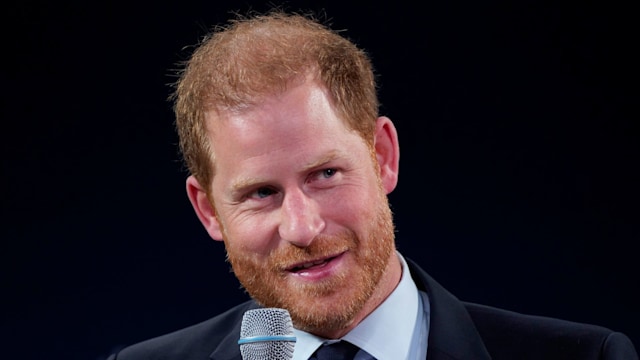 Prince Harry in a suit holding a microphone