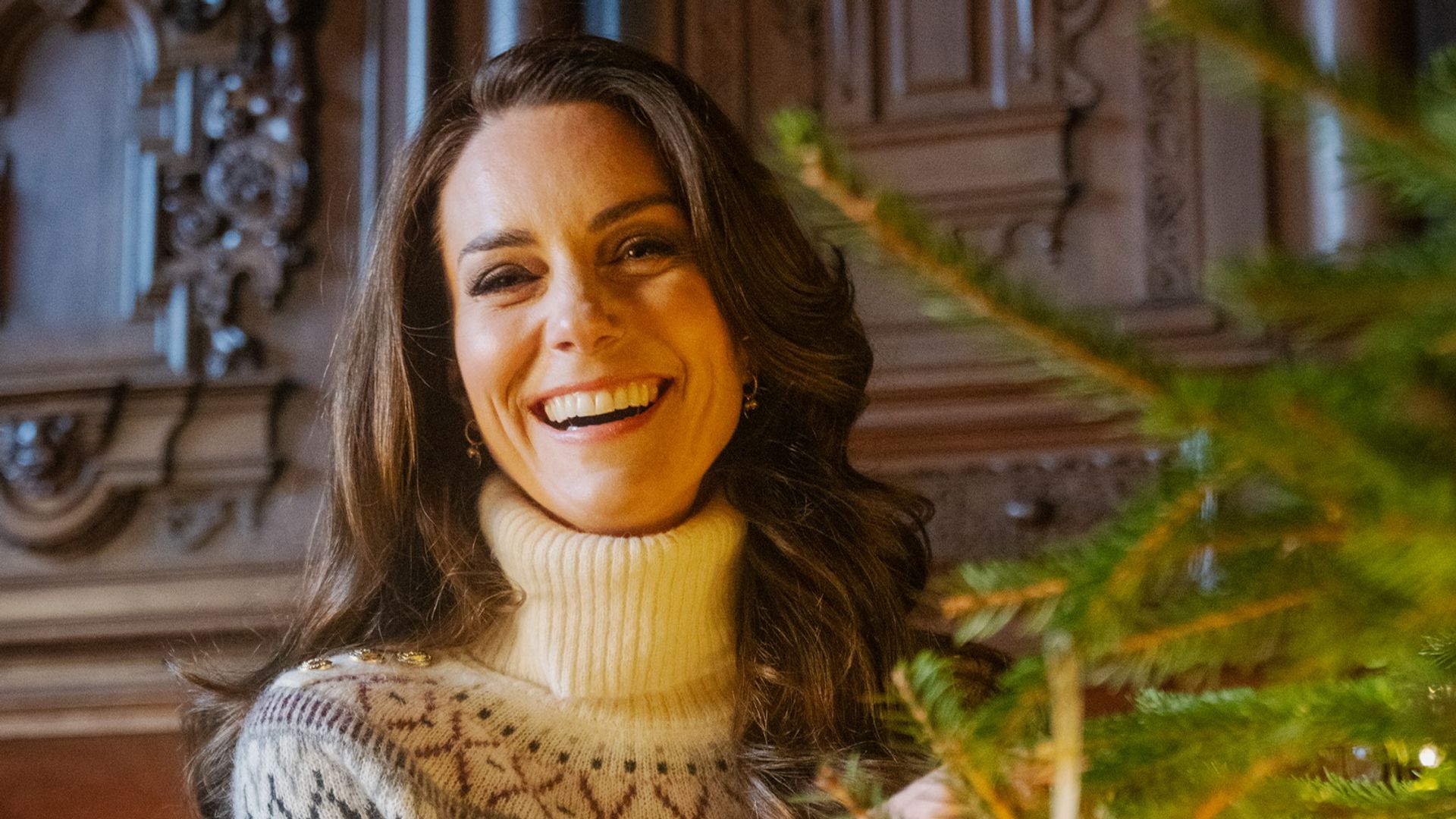 Kate Middleton in a cream jumper decorating a Christmas tree