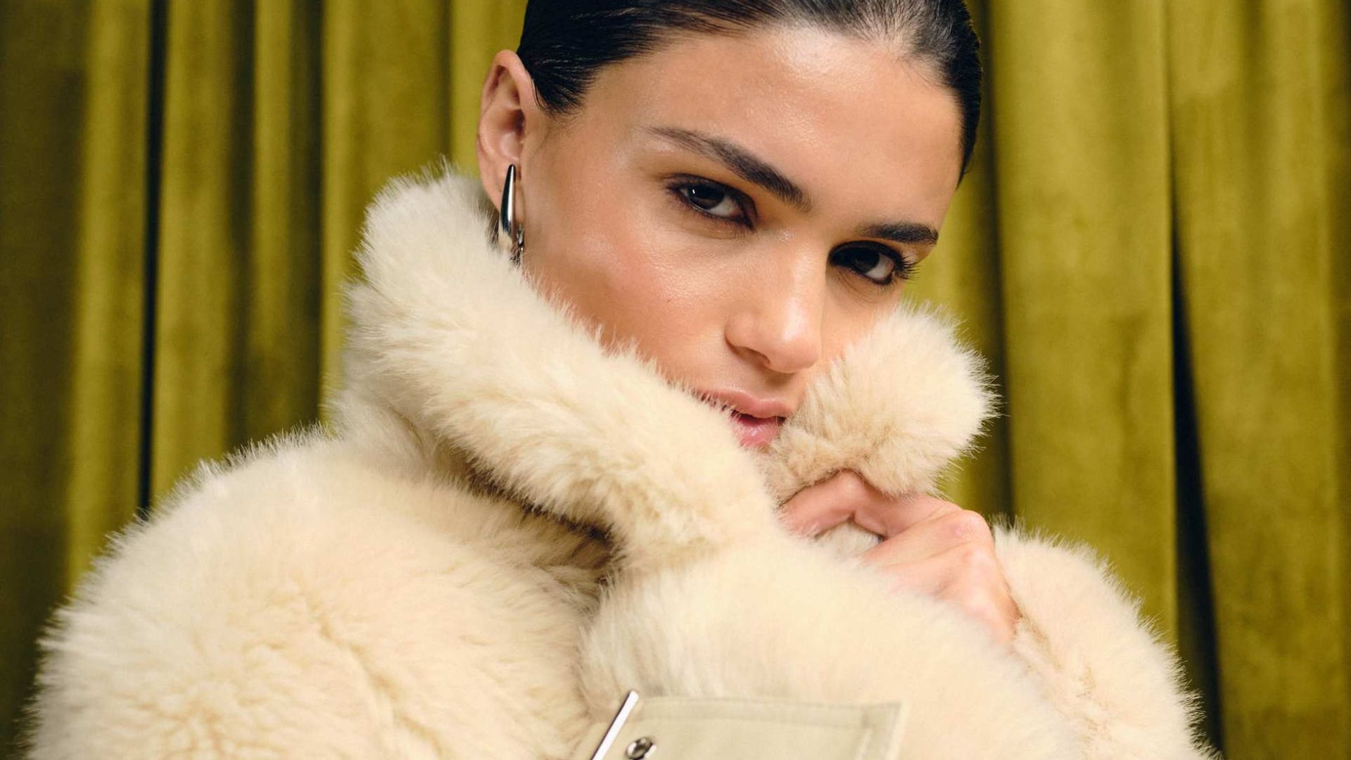 Asos model wearing a firry coat in front of a green background