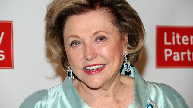 Barbara Taylor Bradford smiling and wearing a turquoise silk top and blue jewelled earings