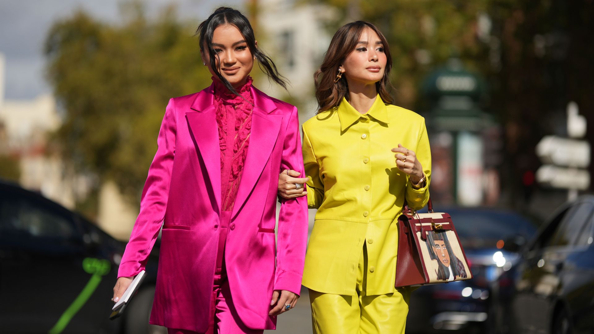 PARIS, FRANCE - OCTOBER 01: Nikki Huang wears diamond earrings, a neon pink ruffled lace print pattern high neck shirt, a neon pink shiny silk / satin long blazer jacket, matching neon pink shiny silk / satin large pants, black shiny leather ankle shoes ,
