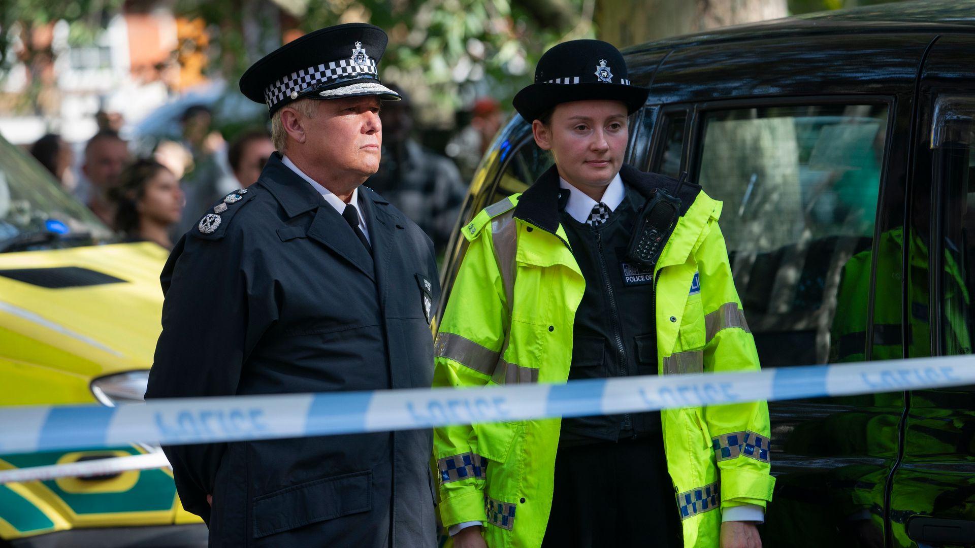 two police officers standing behind police tape