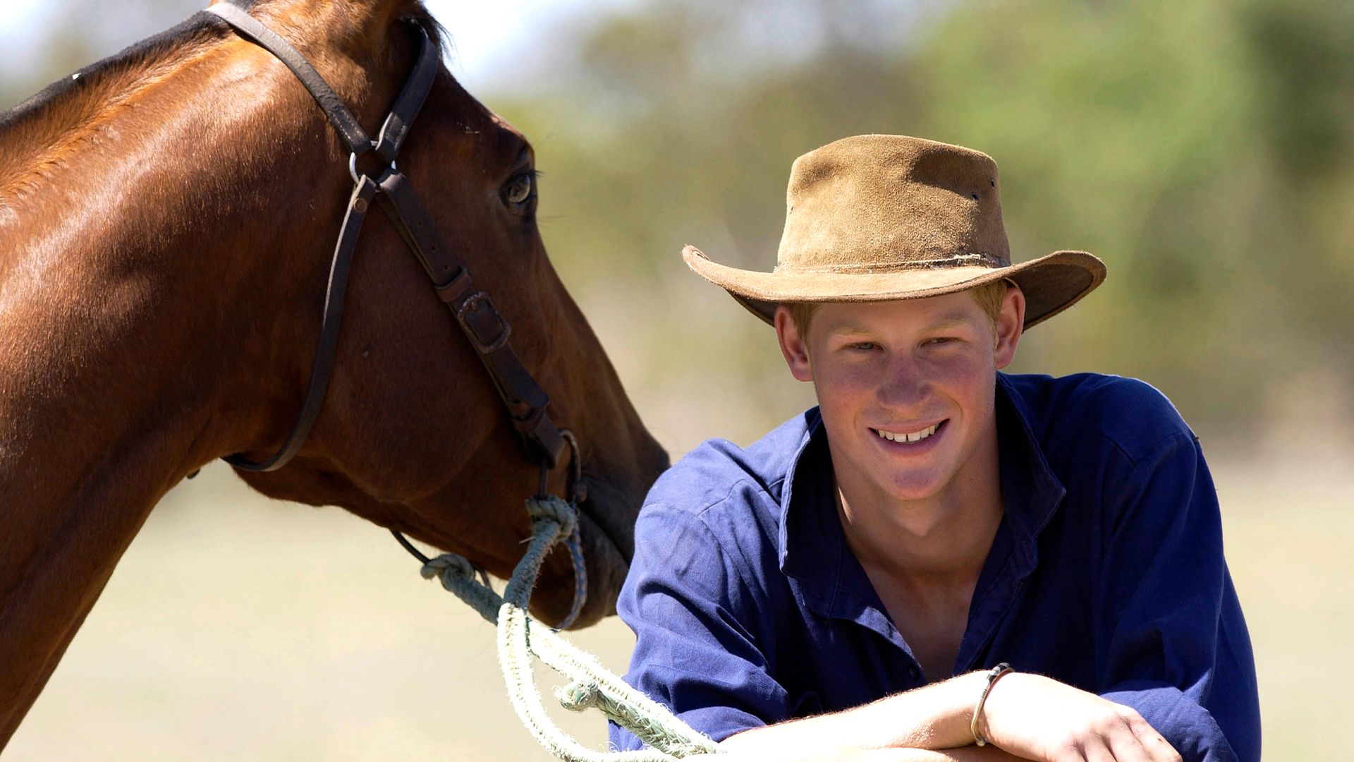Prince Harry in a cowboy hat with a horse