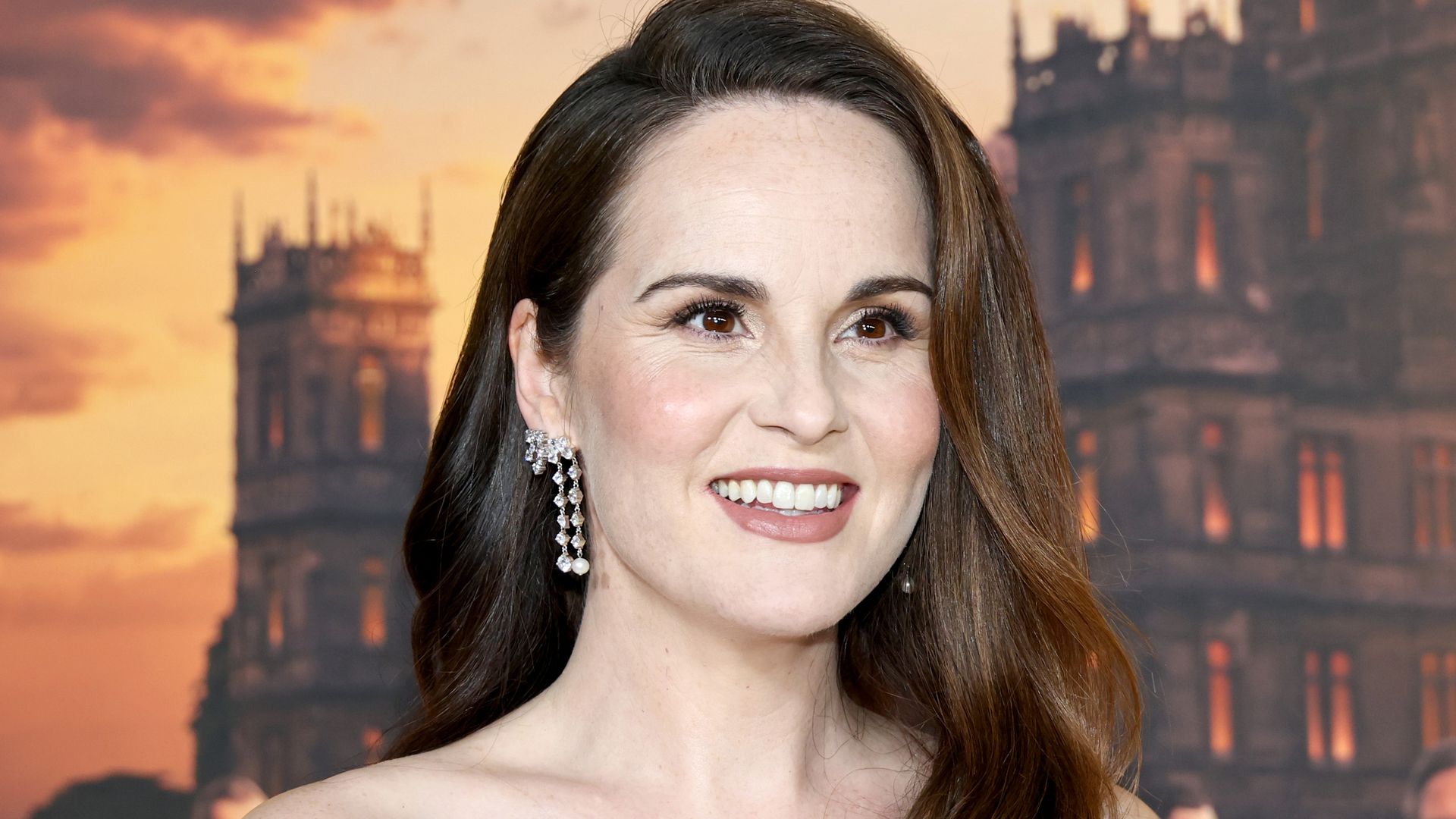 Michelle Dockery smiling in a black strapless dress