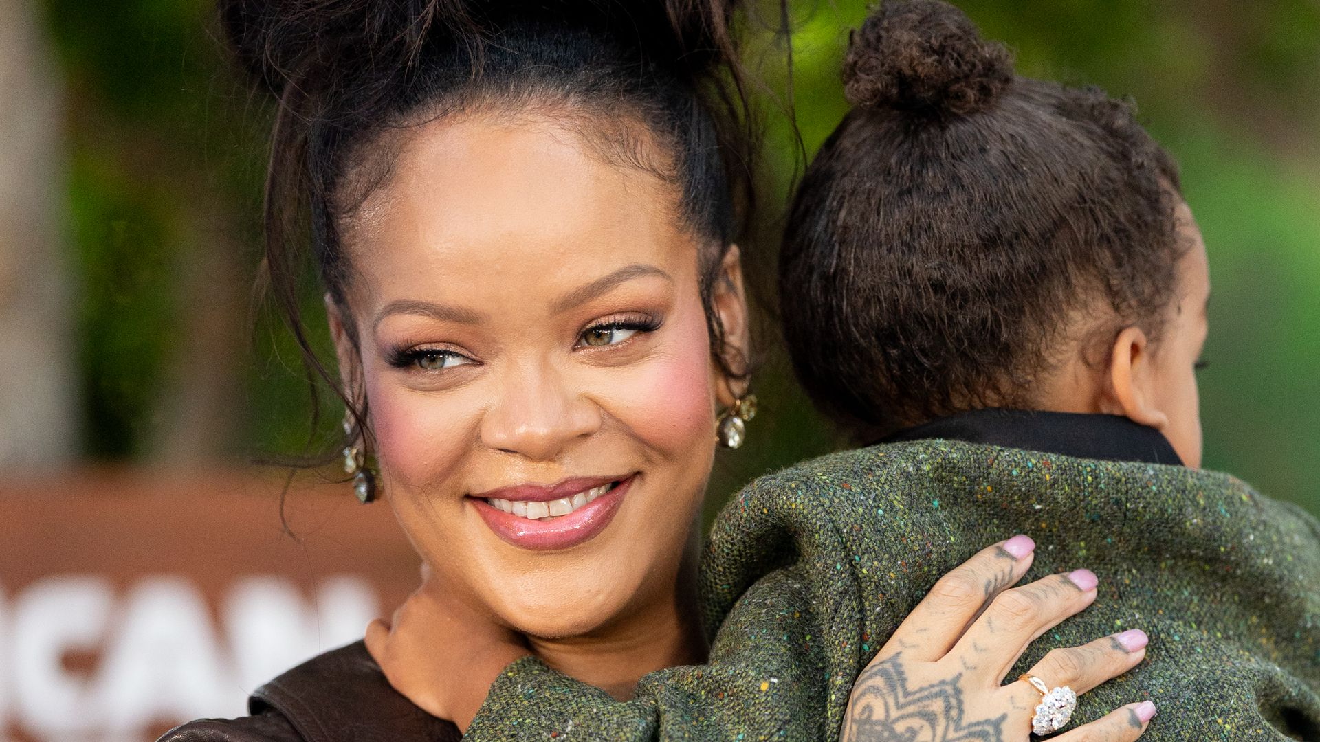 Rihanna in black jacket holding son