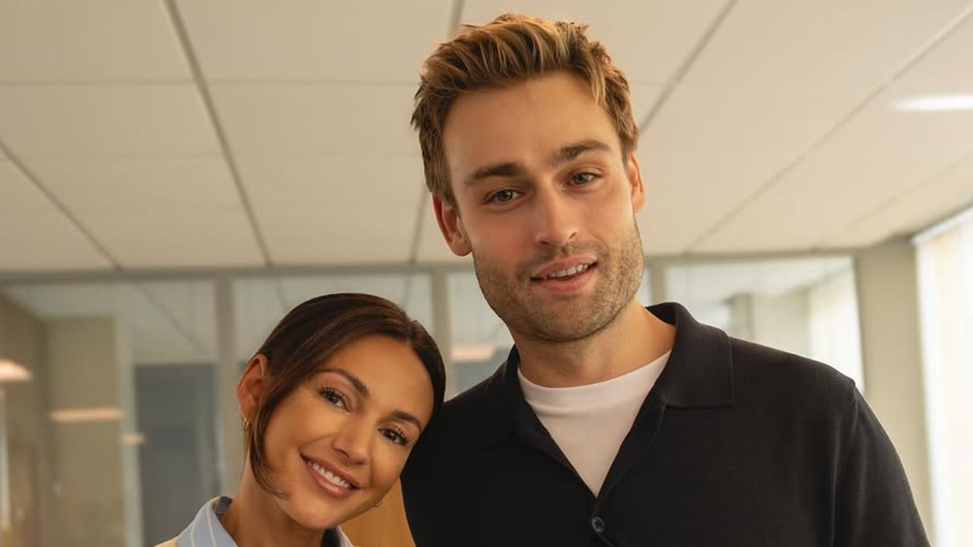 Two people stand holding a movie clapperboard