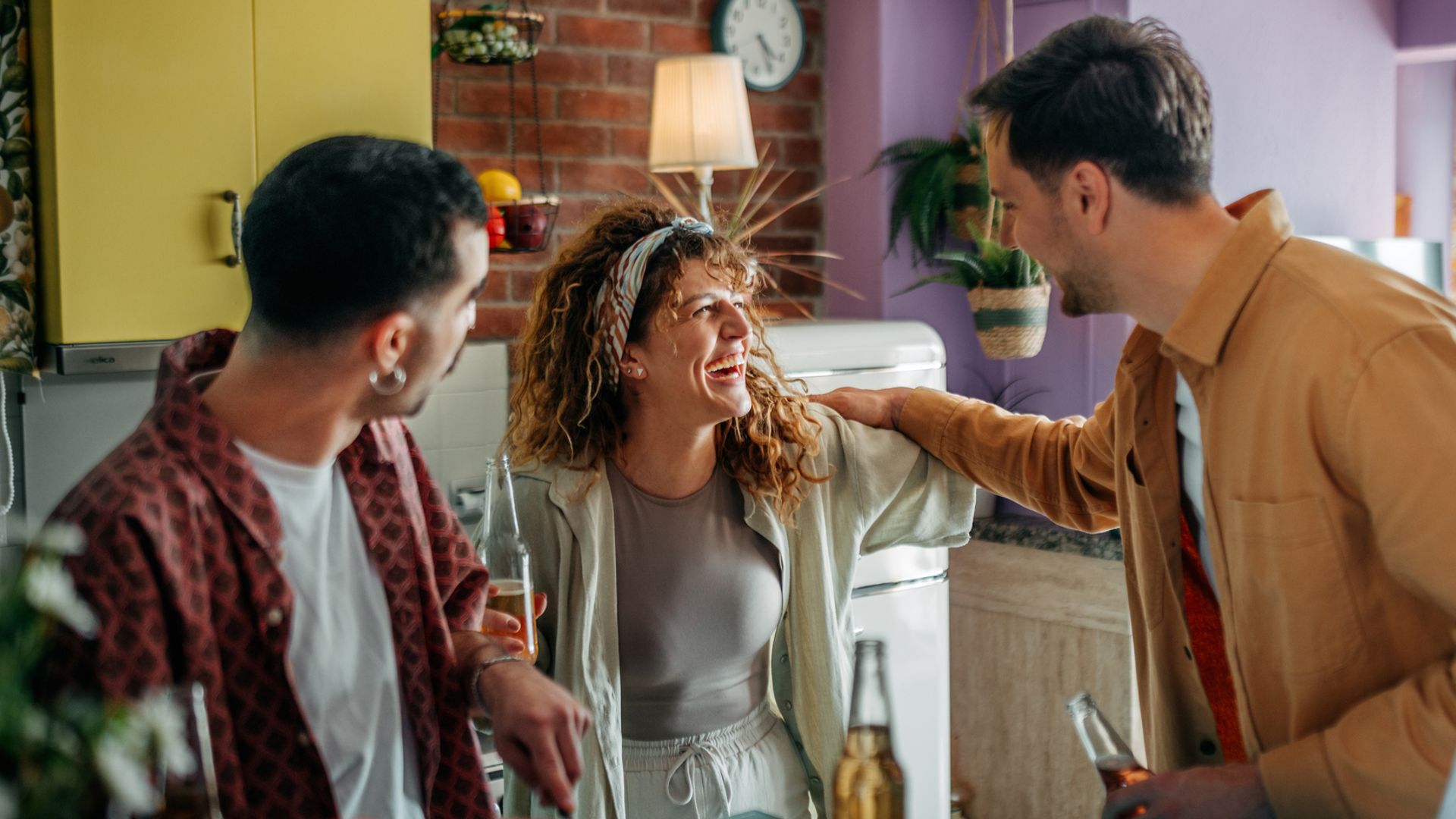 Group of young friends enjoying time together while preparing food and having fun in a cozy domestic kitchen.