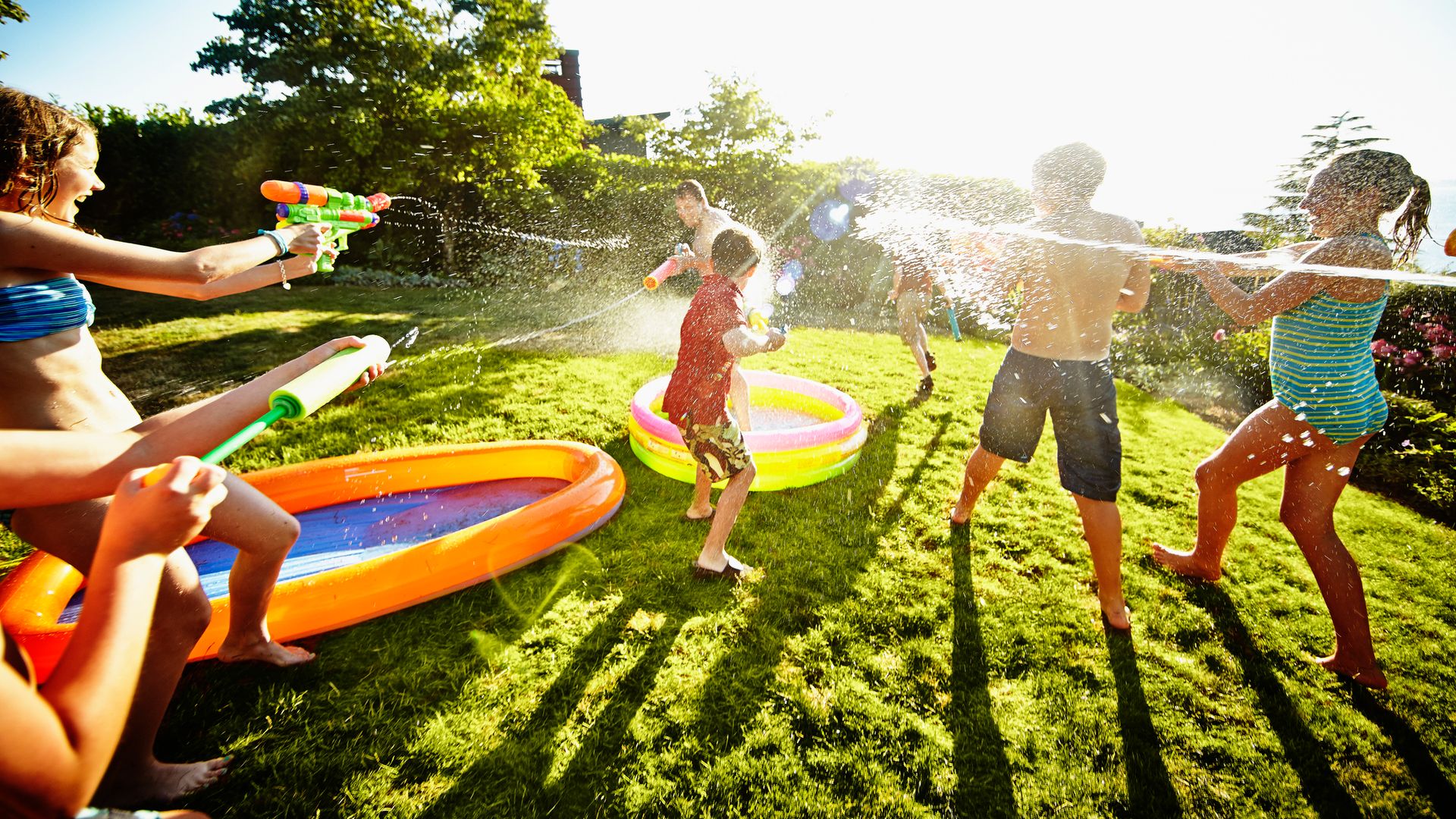 Kids having water fight against dad in garden