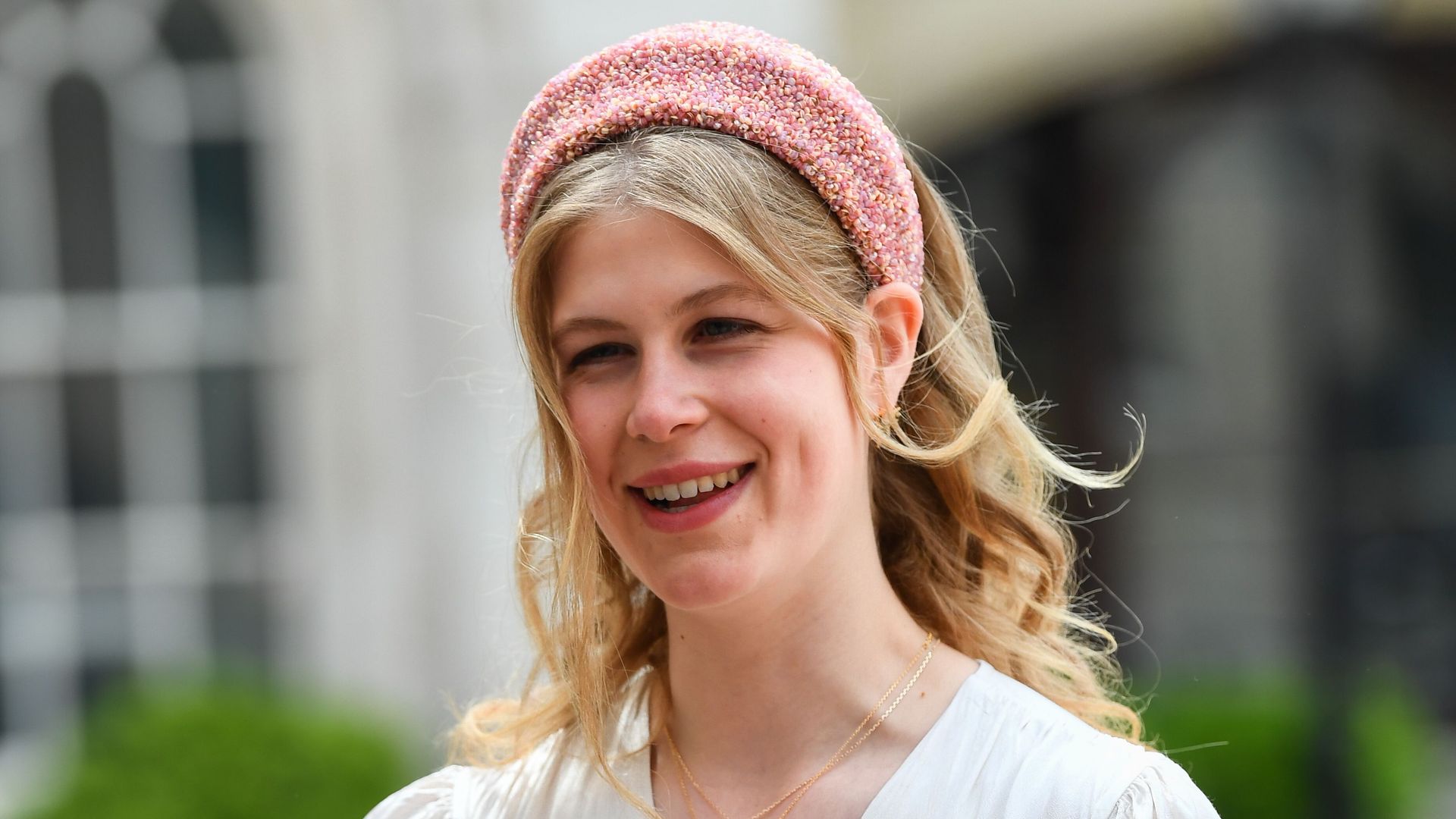Lady Louise smiling in white dress and pink headband