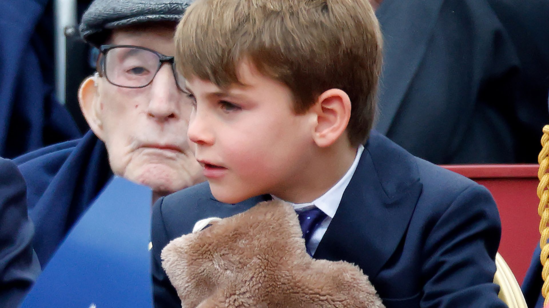 Prince Louis of Wales holds a hot water bottle as he attends a military procession, down The Mall, to mark the 80th anniversary of VE Day on May 5, 2025 in London, England. 