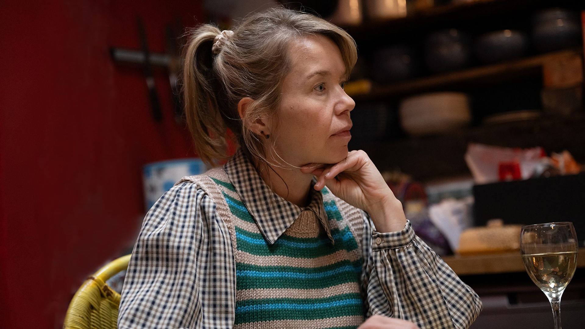 close-up of woman sitting in kitchen with glass of wine