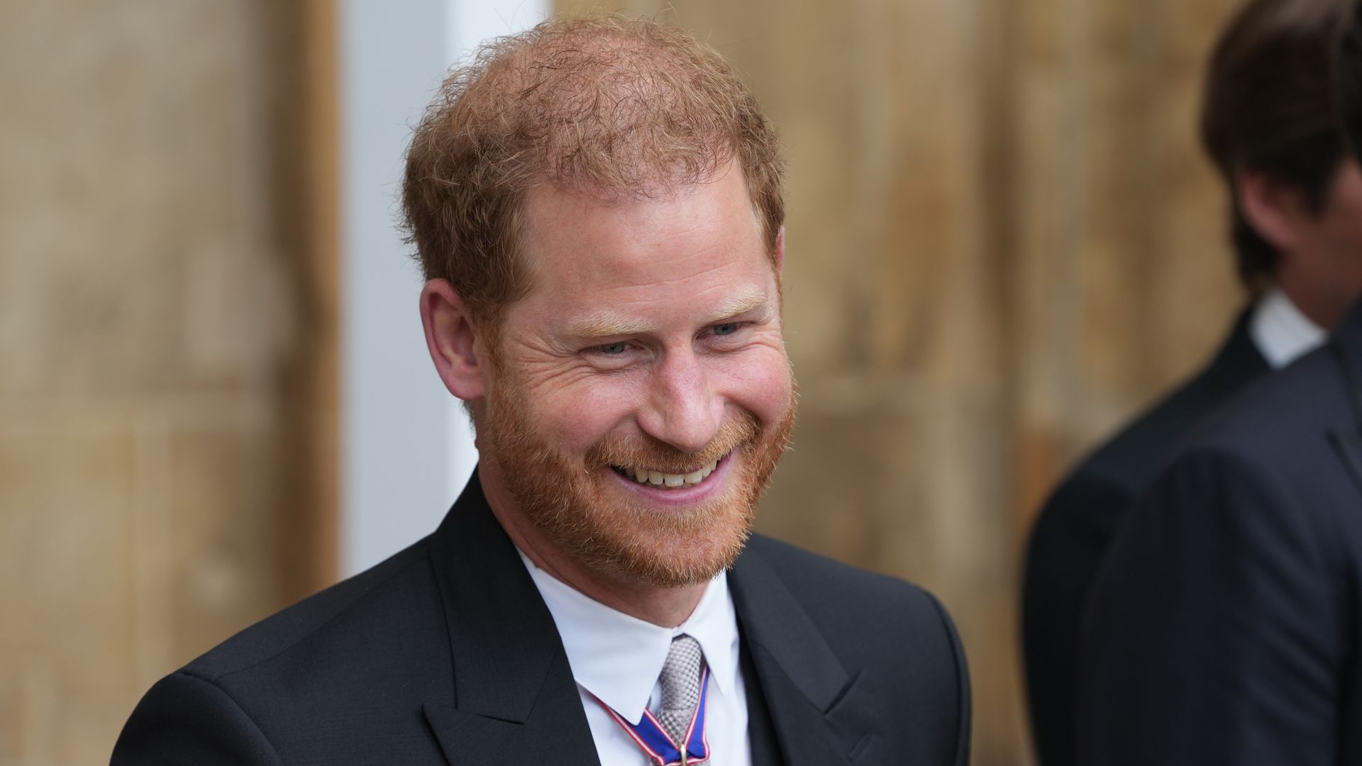 Prince Harry smiling in a black suit