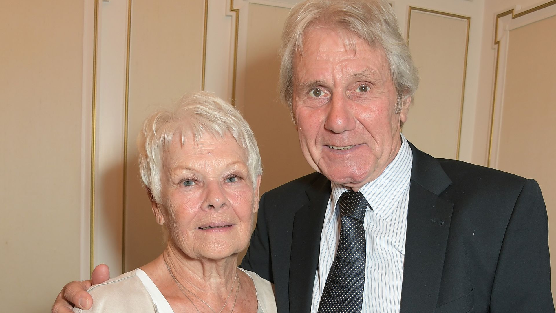Dame Judi Dench in white and David Mills in a black suit