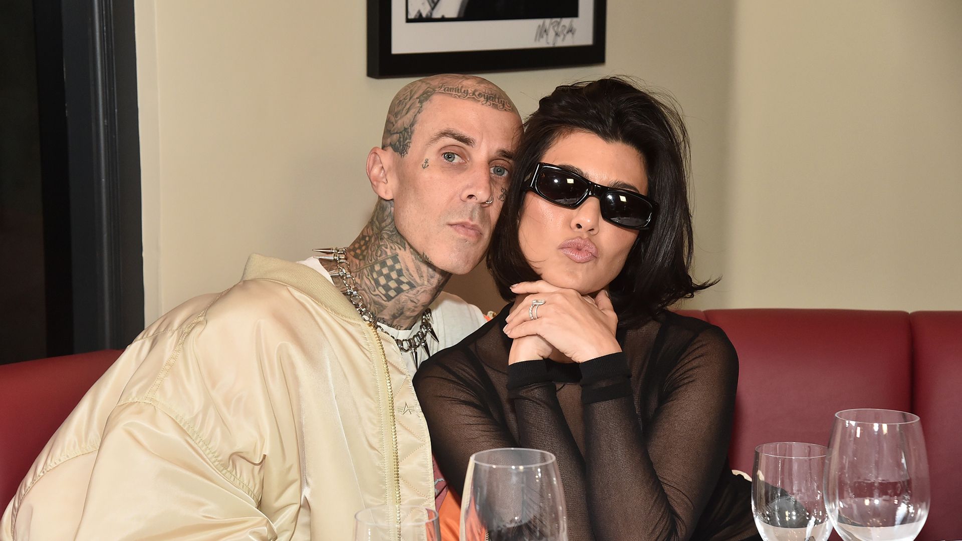 Kourtney Kardashian and Travis Barker sitting in a restaurant booth together