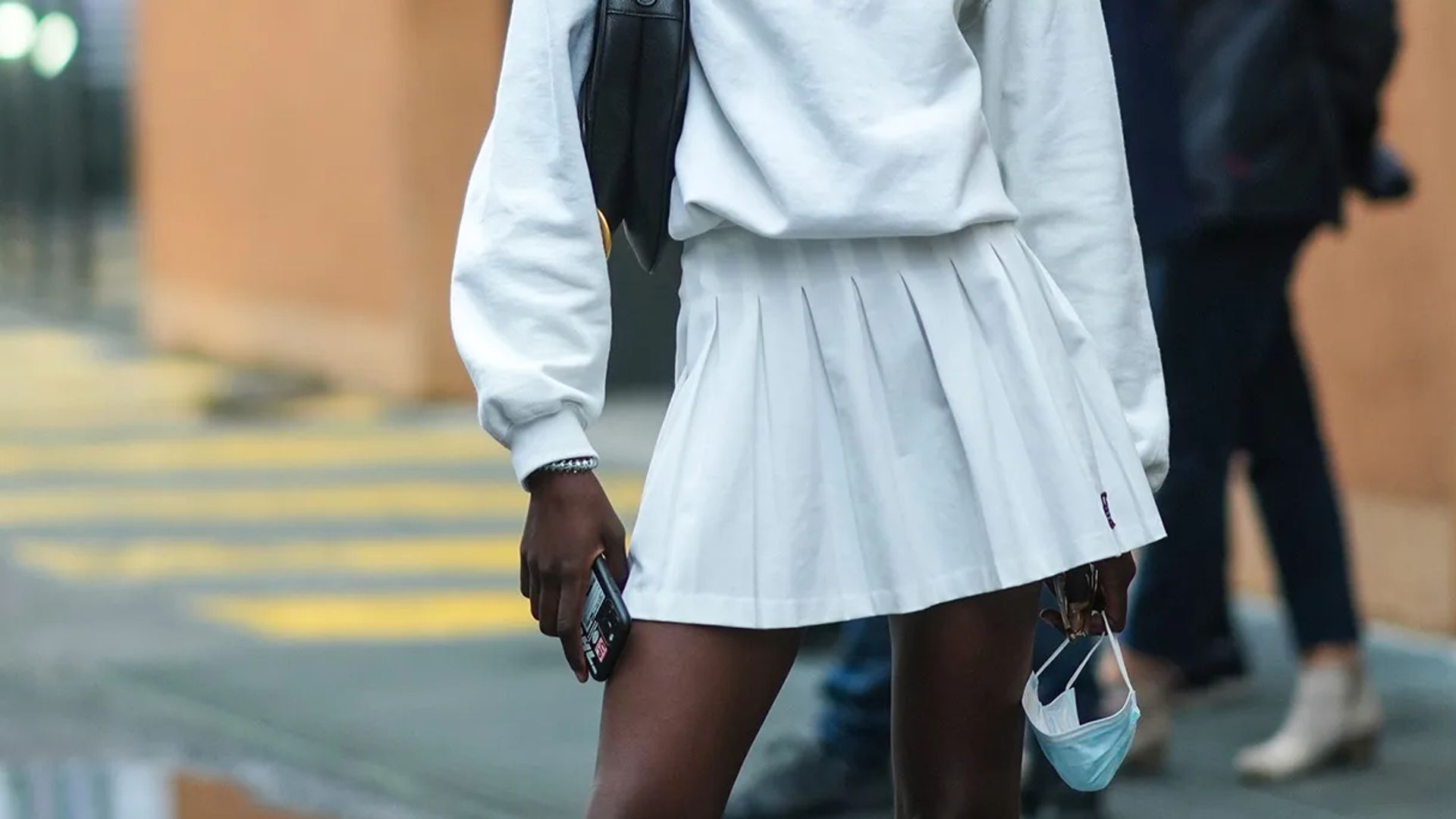model in white tennis skirt and sweatshirt
