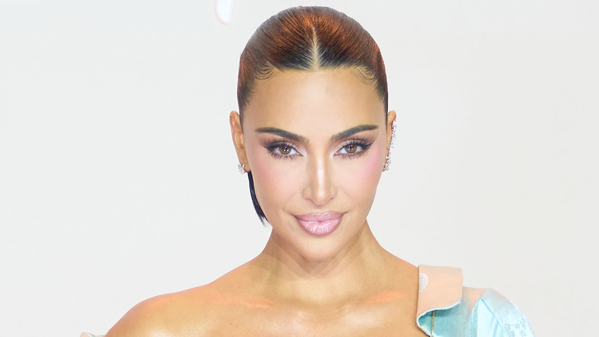 Kim Kardashian wears a structured off-the-shoulder satin and lustrous maxi gown, low-neck dress by Christian Dior Spring/Summer 2000 collection, in icy blue with sculpted draping, asymmetrical neckline and fitted mermaid silhouette, featuring jacquard floral motifs embroidery and front zipper detail, sleek parted pulled-back hair, jewelry by Repossi, and attends the "All's Fair" Disney+ Premiere at Maison de La Chimie on October 21, 2025 in Paris, France. (Photo by Edward Berthelot/WireImage)