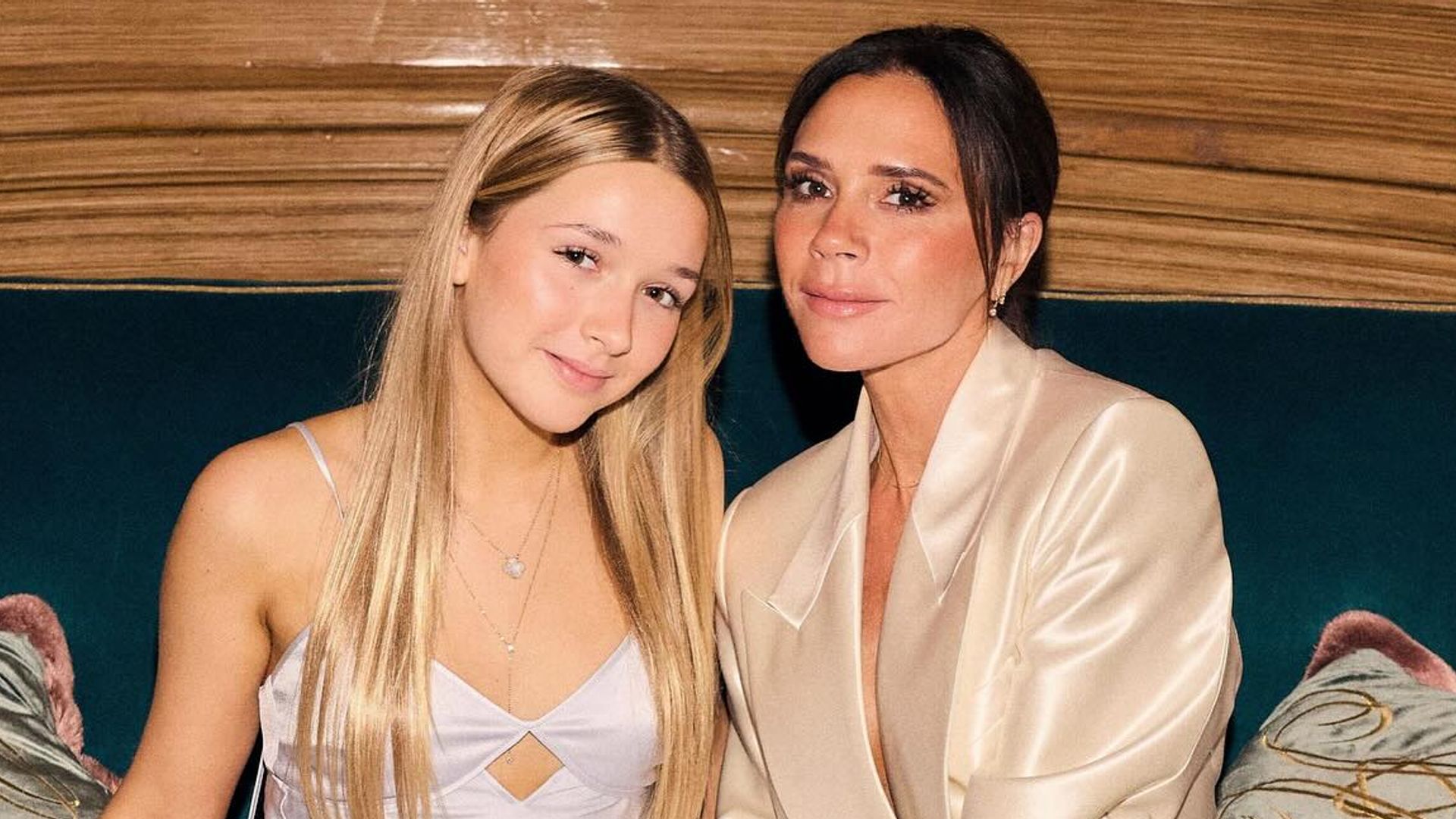 Victoria and Harper Beckham pose on a couch in silky outfits