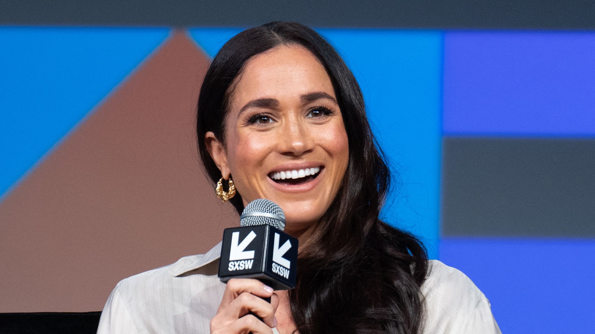 Meghan Markle in a white shirt with a microphone