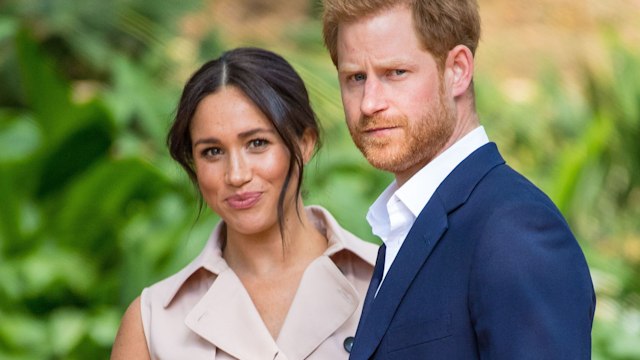 meghan markle in trench dress and prince harry in navy suit in garden