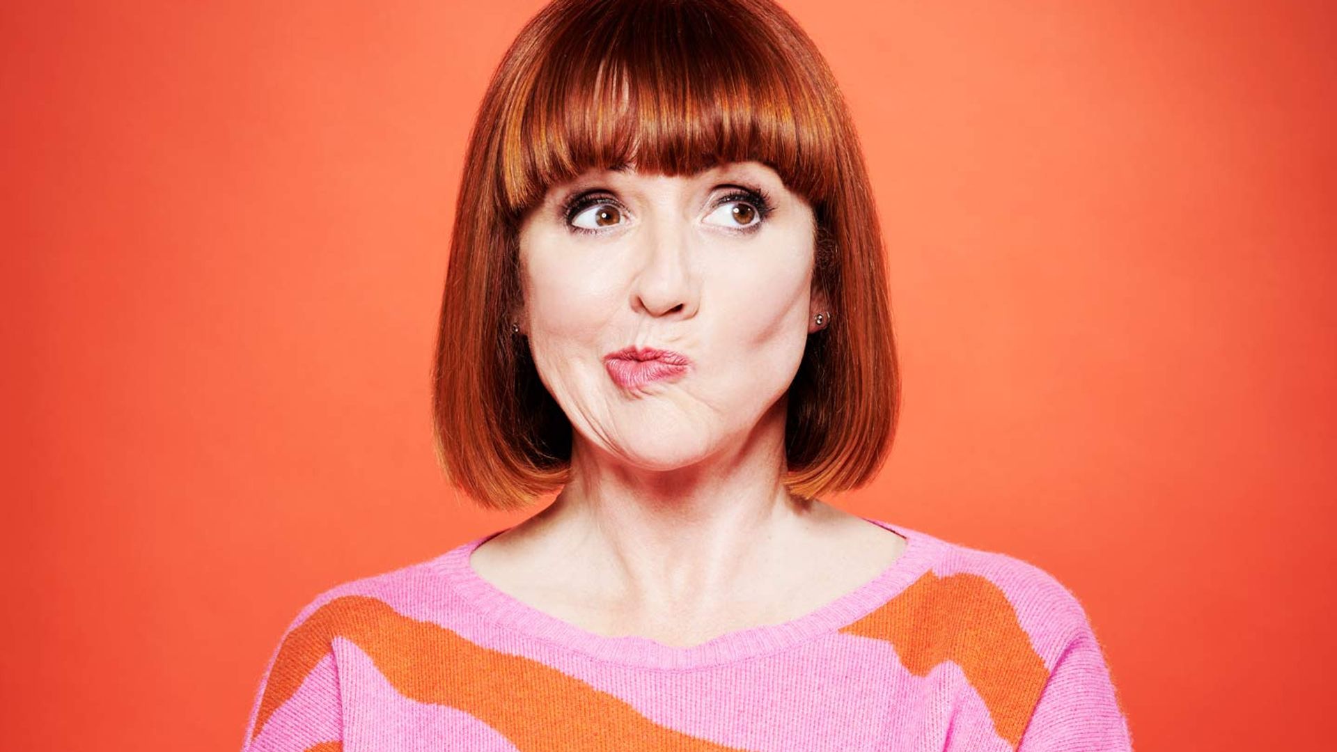 Woman in pink and orange striped jumper pulling a face for the camera
