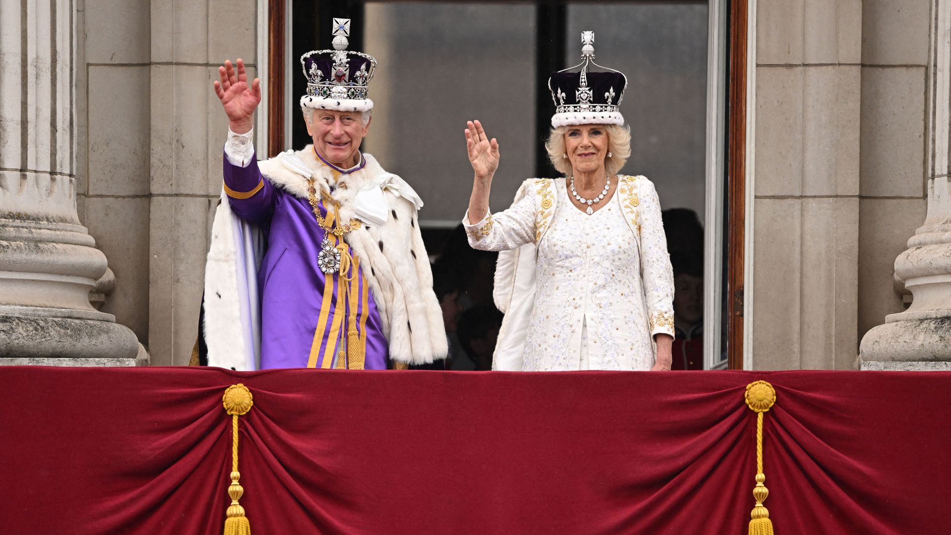 King Charles and Queen Camilla waving from a balcony