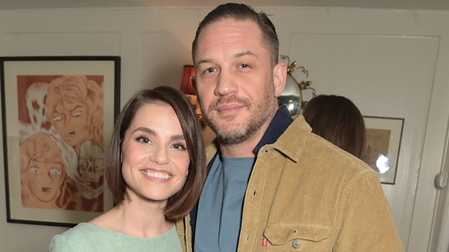 Charlotte Riley and Tom Hardy stand side by side and smile for a photo while visiting Soho House in London for an event