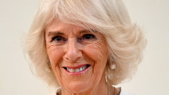 Queen Camilla smiling in white dress