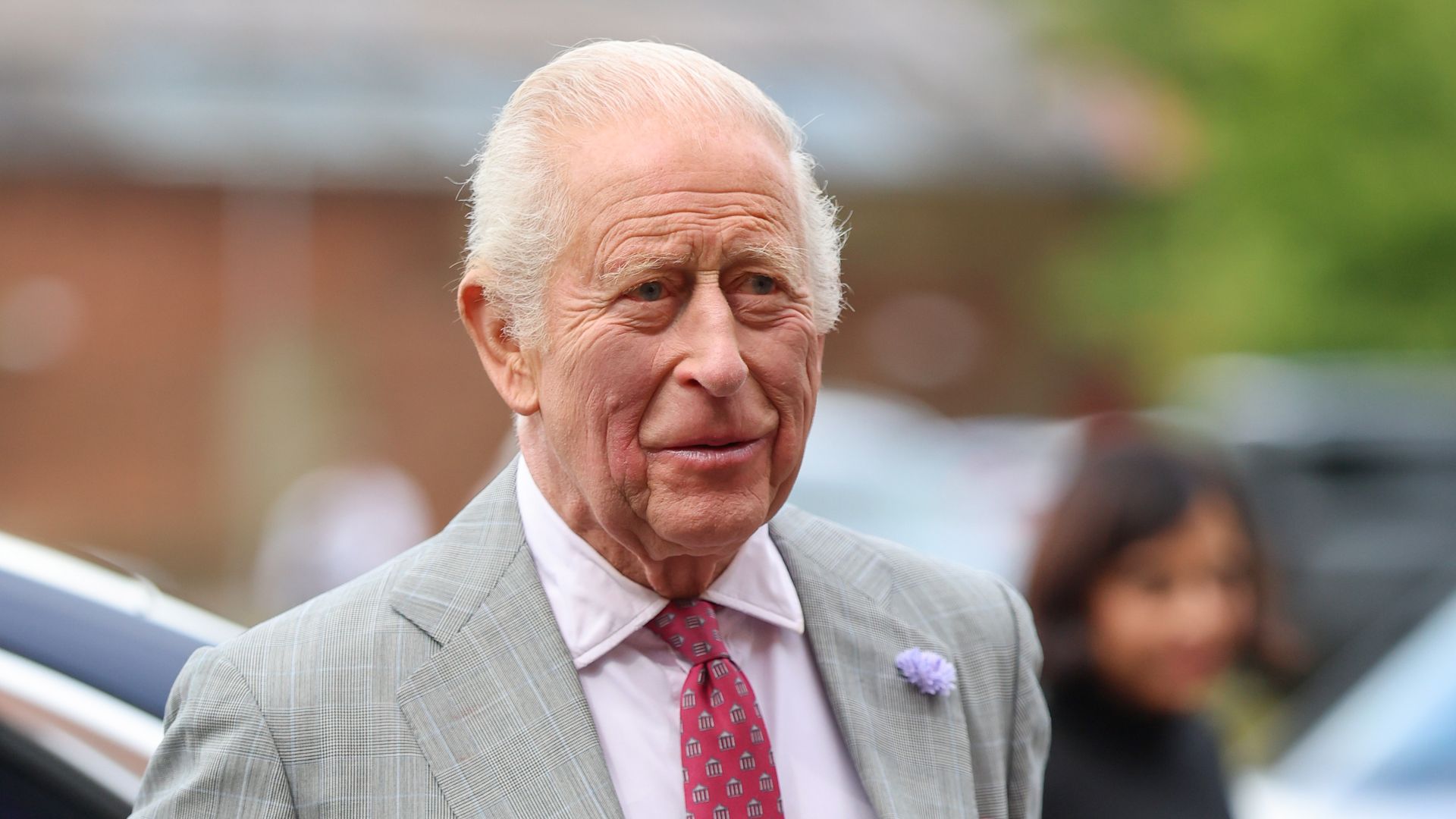 King Charles smiling in grey suit in Birmingham