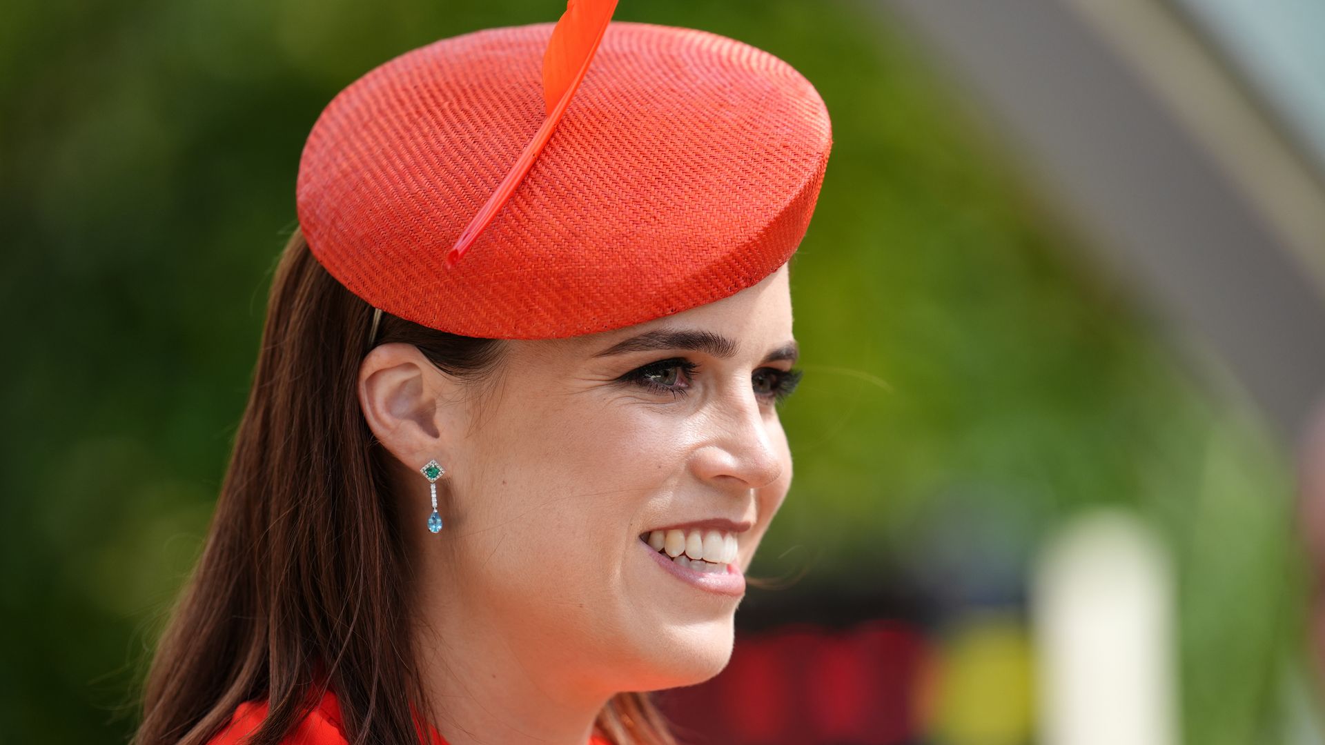 Princess Eugenie side on smiling in red hat