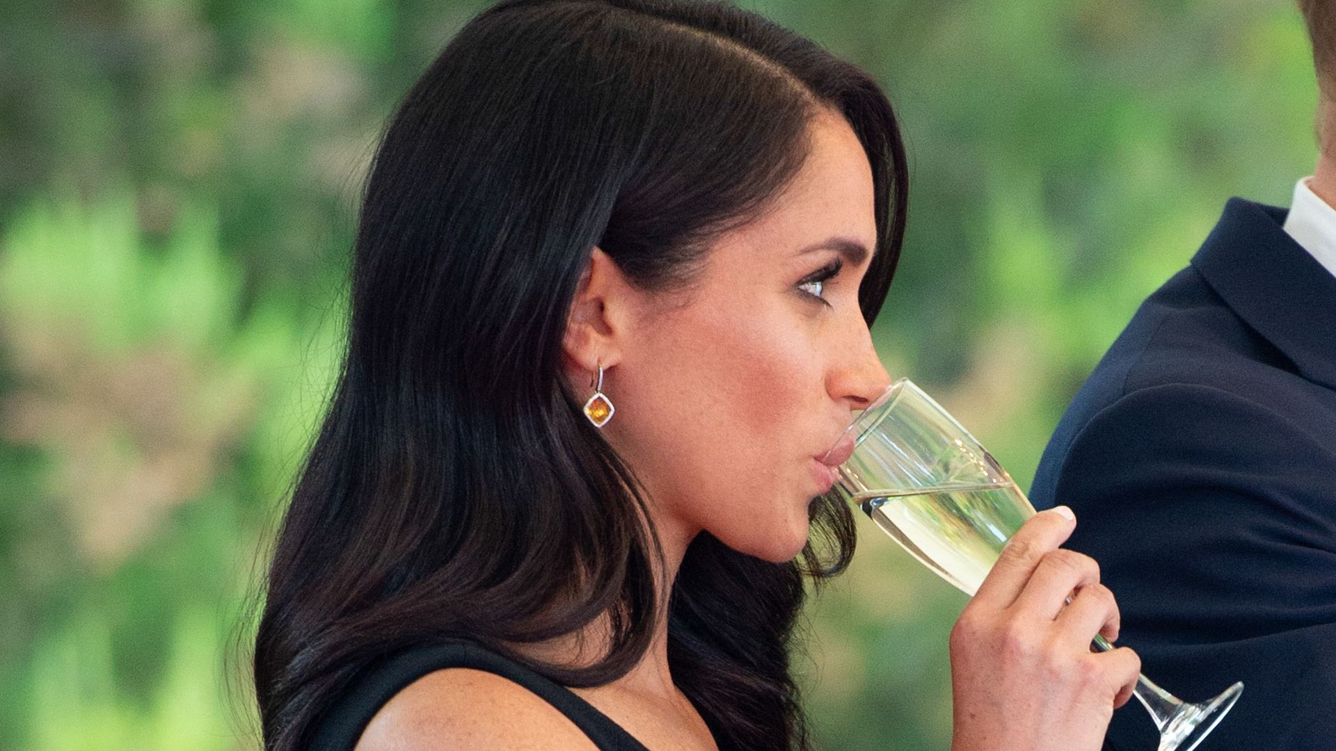Duchess of Sussex sipping champagne in a black dress